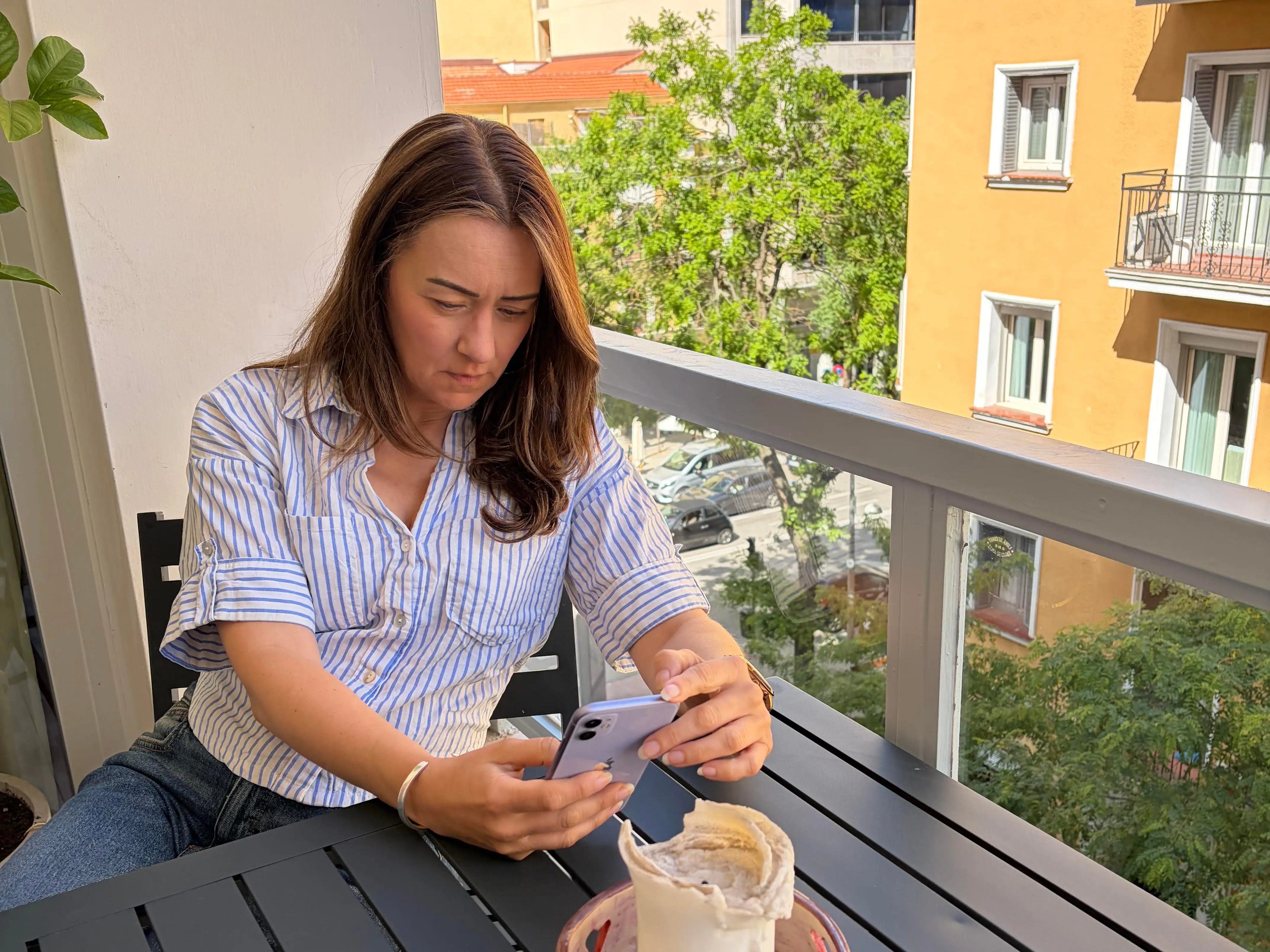 A woman sitting on the balcony looking at her phone.