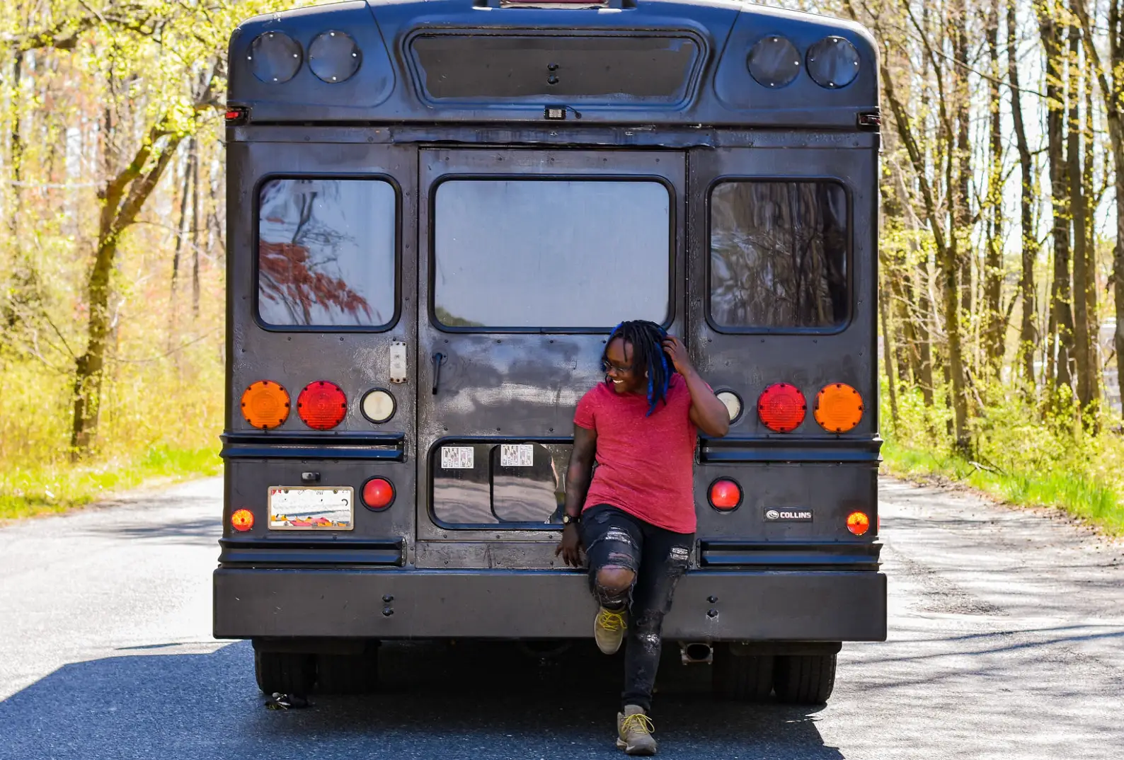 The writer standing in front of a converted van, wearing a red T-shirt.