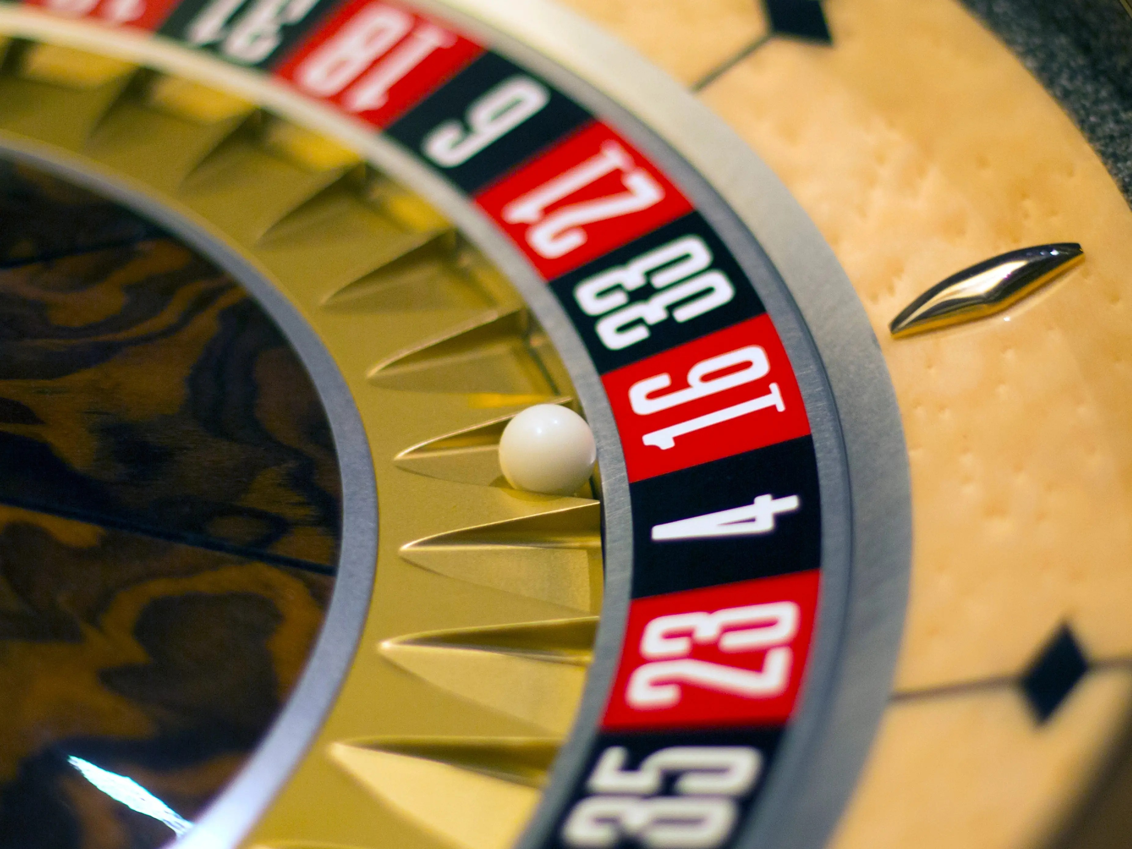A close-up of a roulette wheel with a ball near the number 16