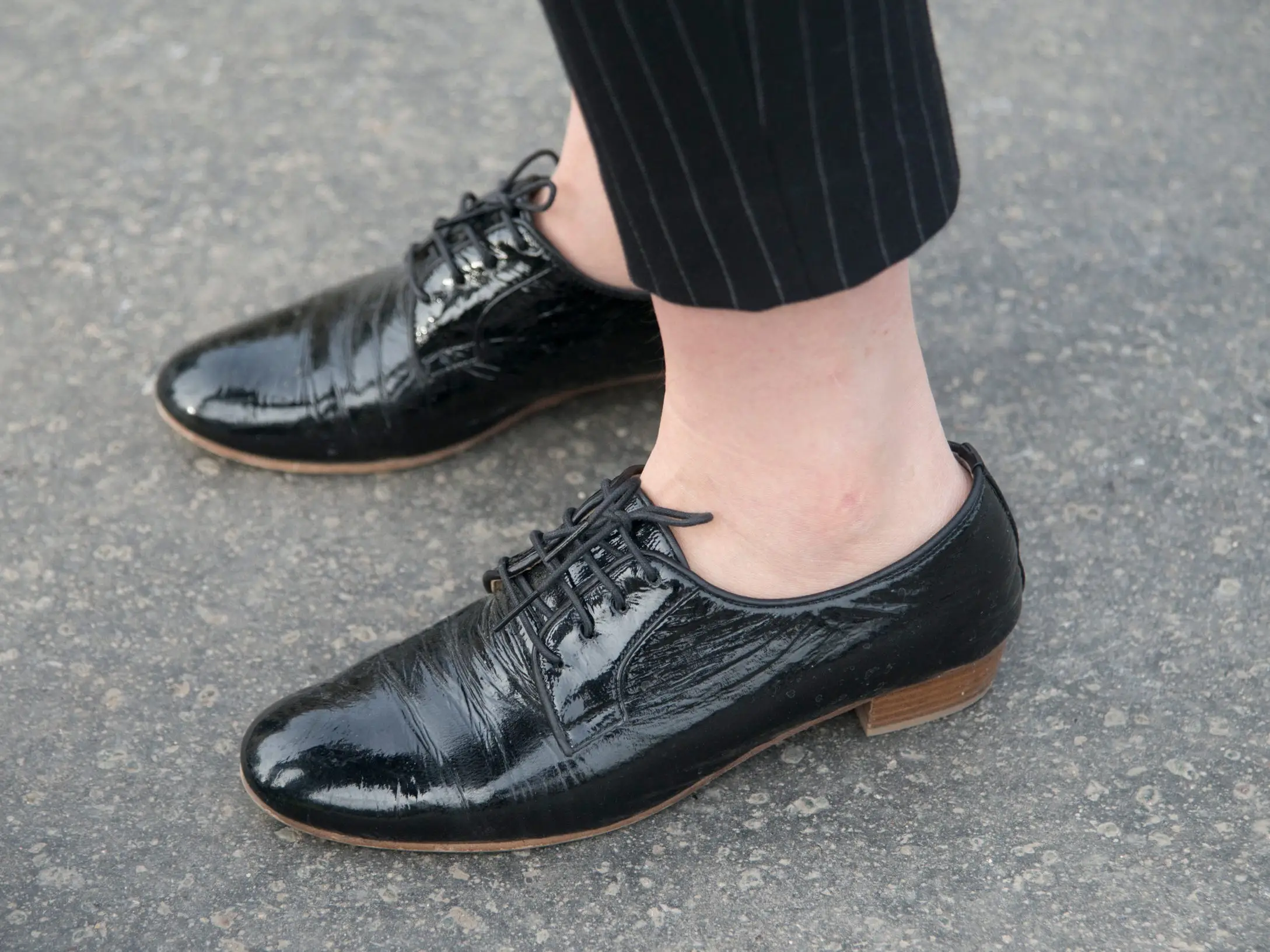 A woman wearing a pair of black leather Derby shoes that lace up and sit low to the ground.