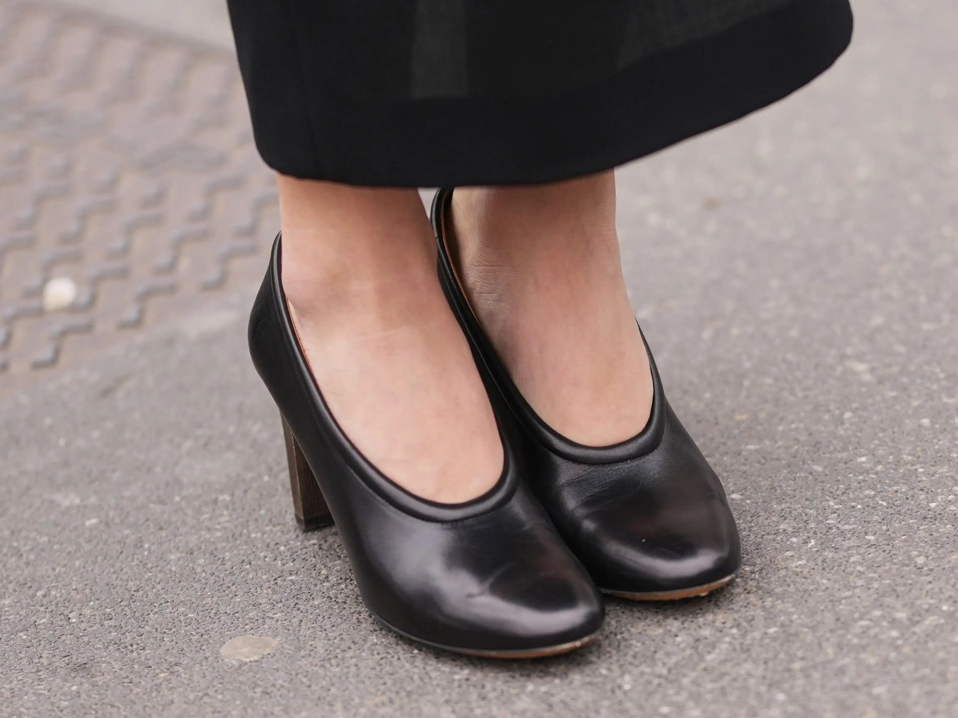 A woman wearing a pair of round-toed black heels.
