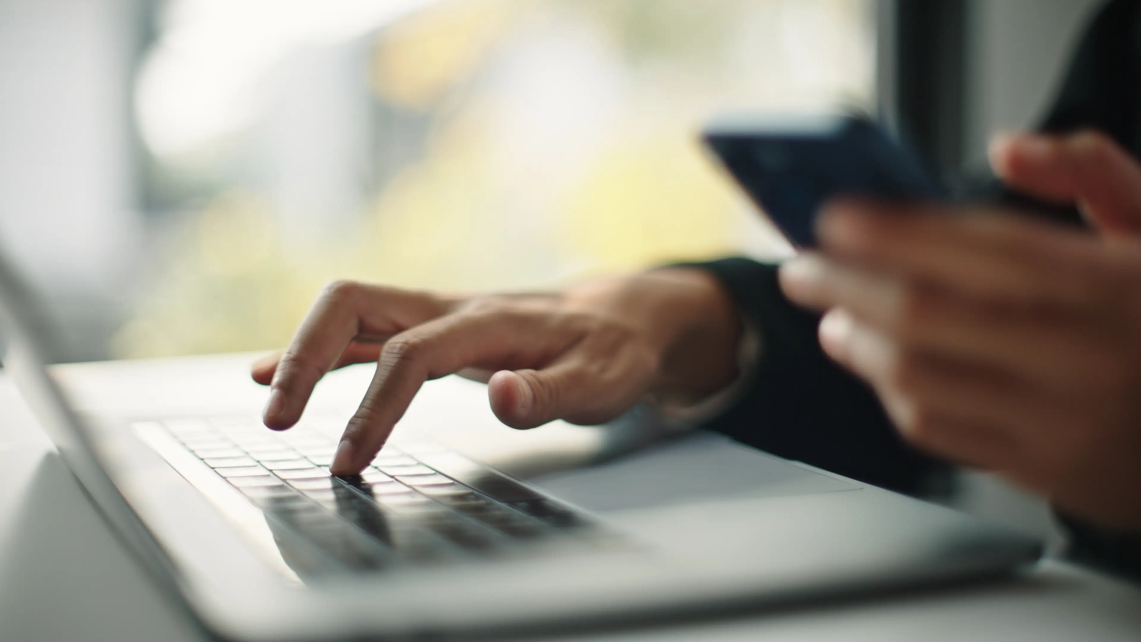 Person holding phone with laptop next to it