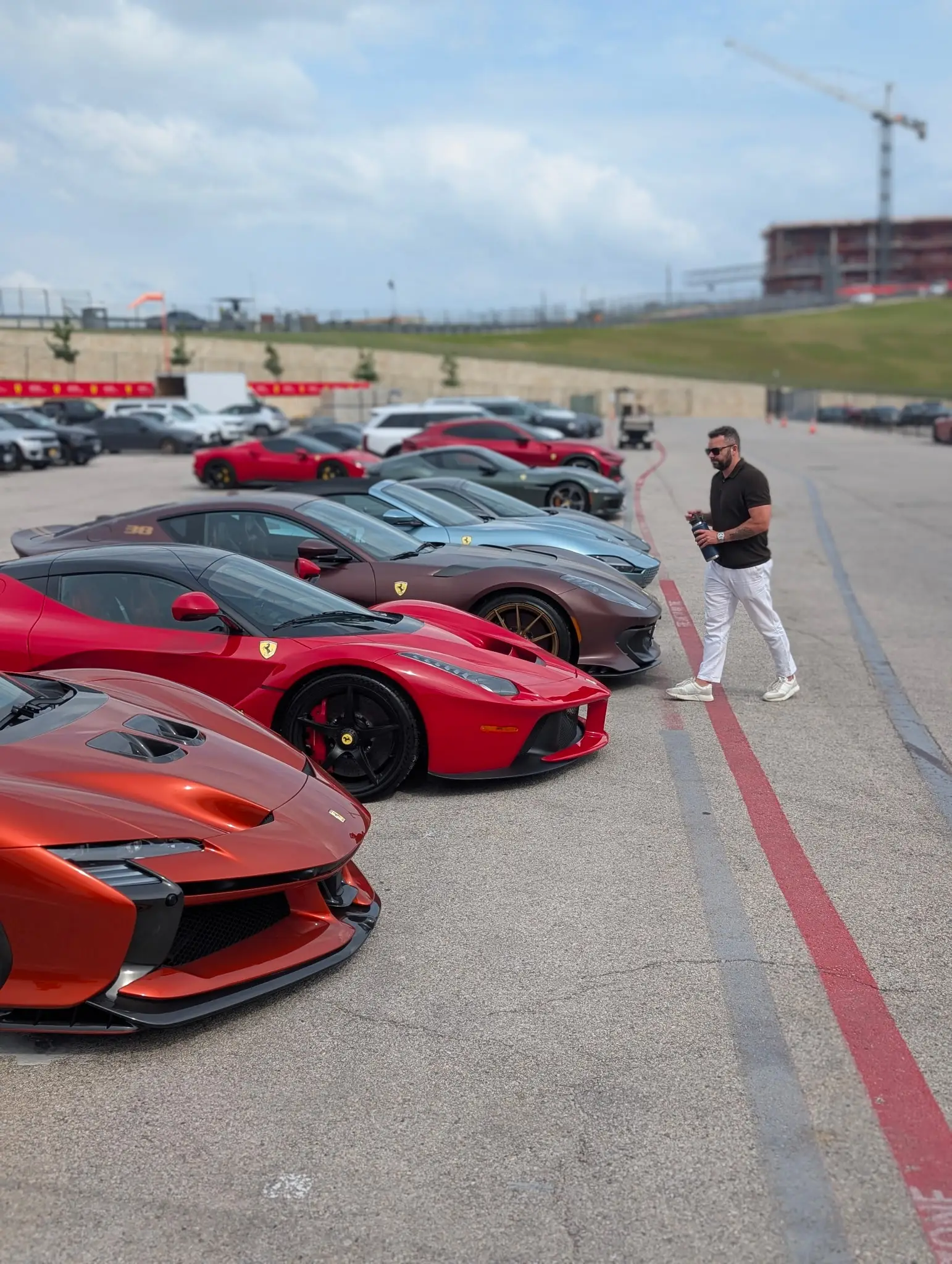 A man standing in front of a lot full of luxury cars.
