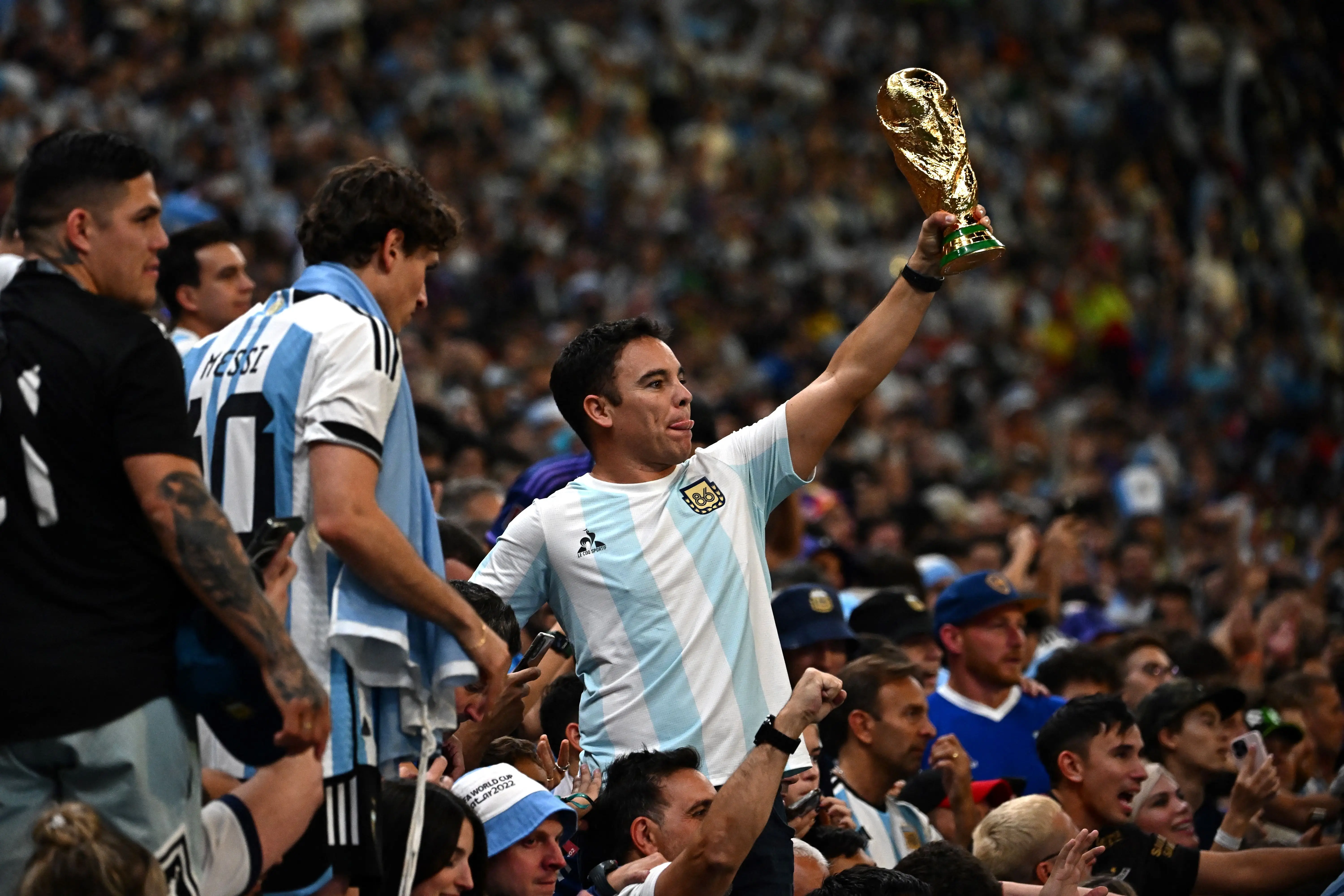 An Argentina supporter holds a replica of the FIFA World Cup Trophy after Argentina won the Qatar 2022 World Cup final football match between Argentina and France at Lusail Stadium in Lusail, north of Doha on December 18, 2022.
