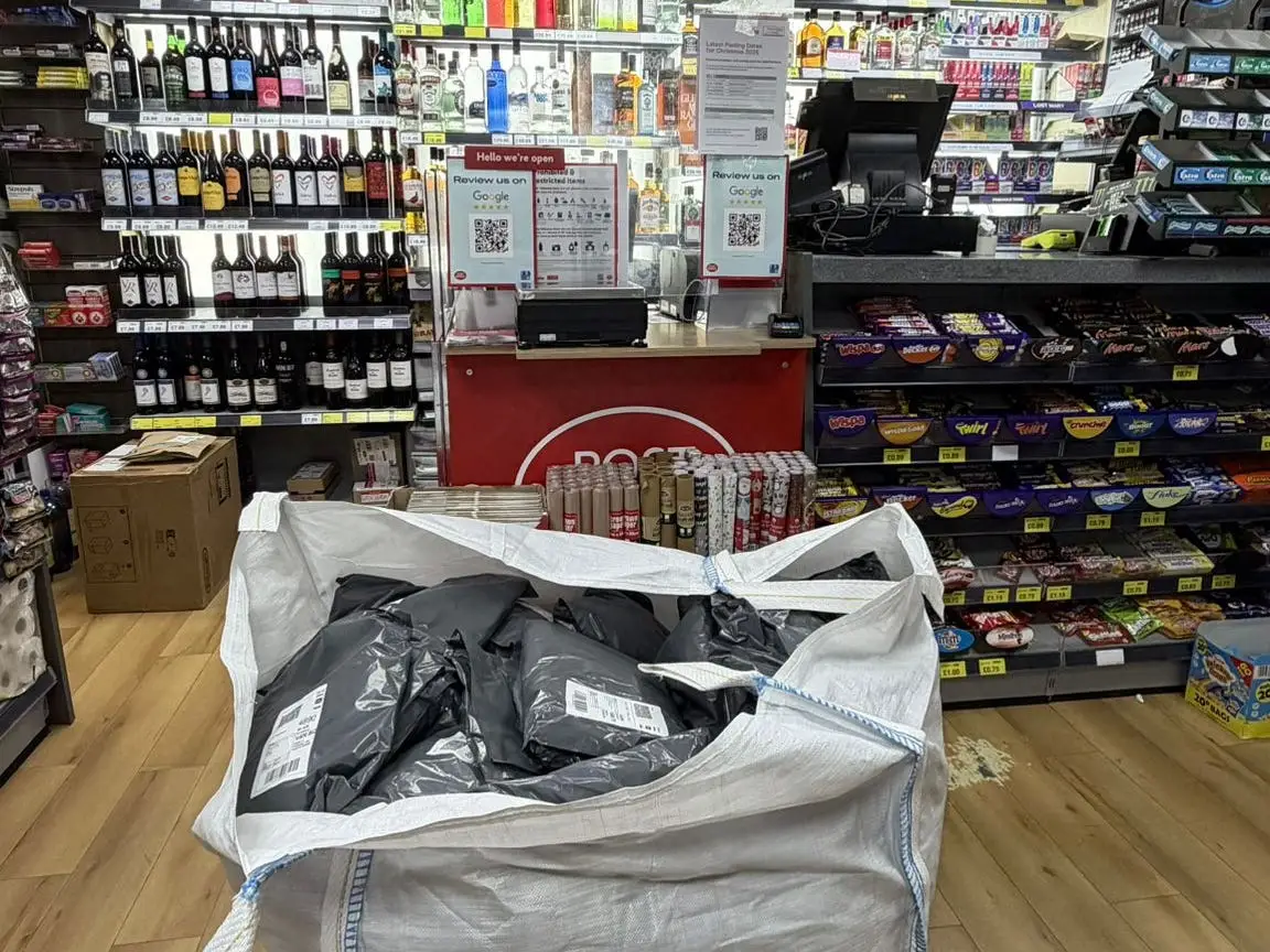 Big bag full of parcels placed in front of a Post Office stand.