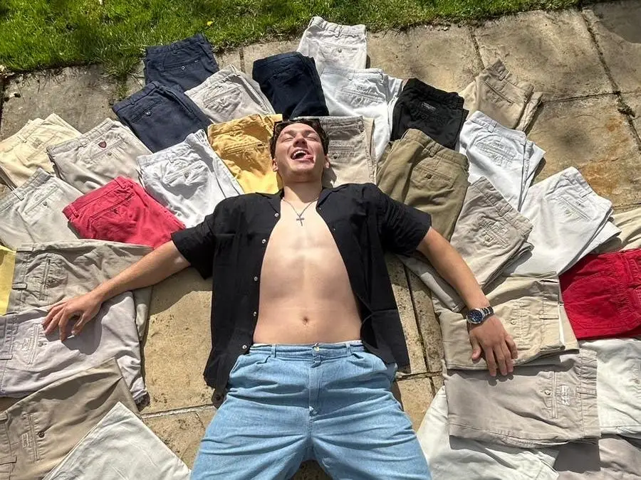 Morgan Purnell lies on the ground outside with several pairs of folded Ralph Lauren trousers surrounding him.
