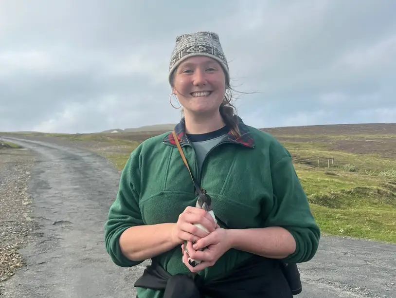 The writer standing on a street in a remote area, holding a bird in her hand.
