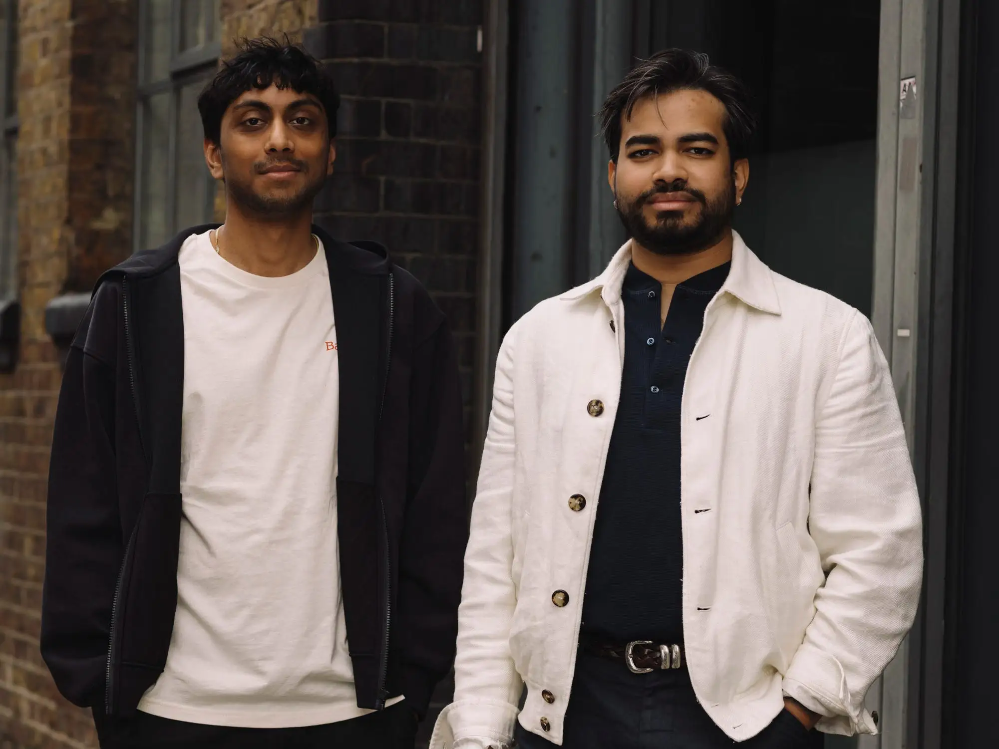 Tilt cofounders Neil Shah and Abhi Thanendran pose in front of. a door outside.