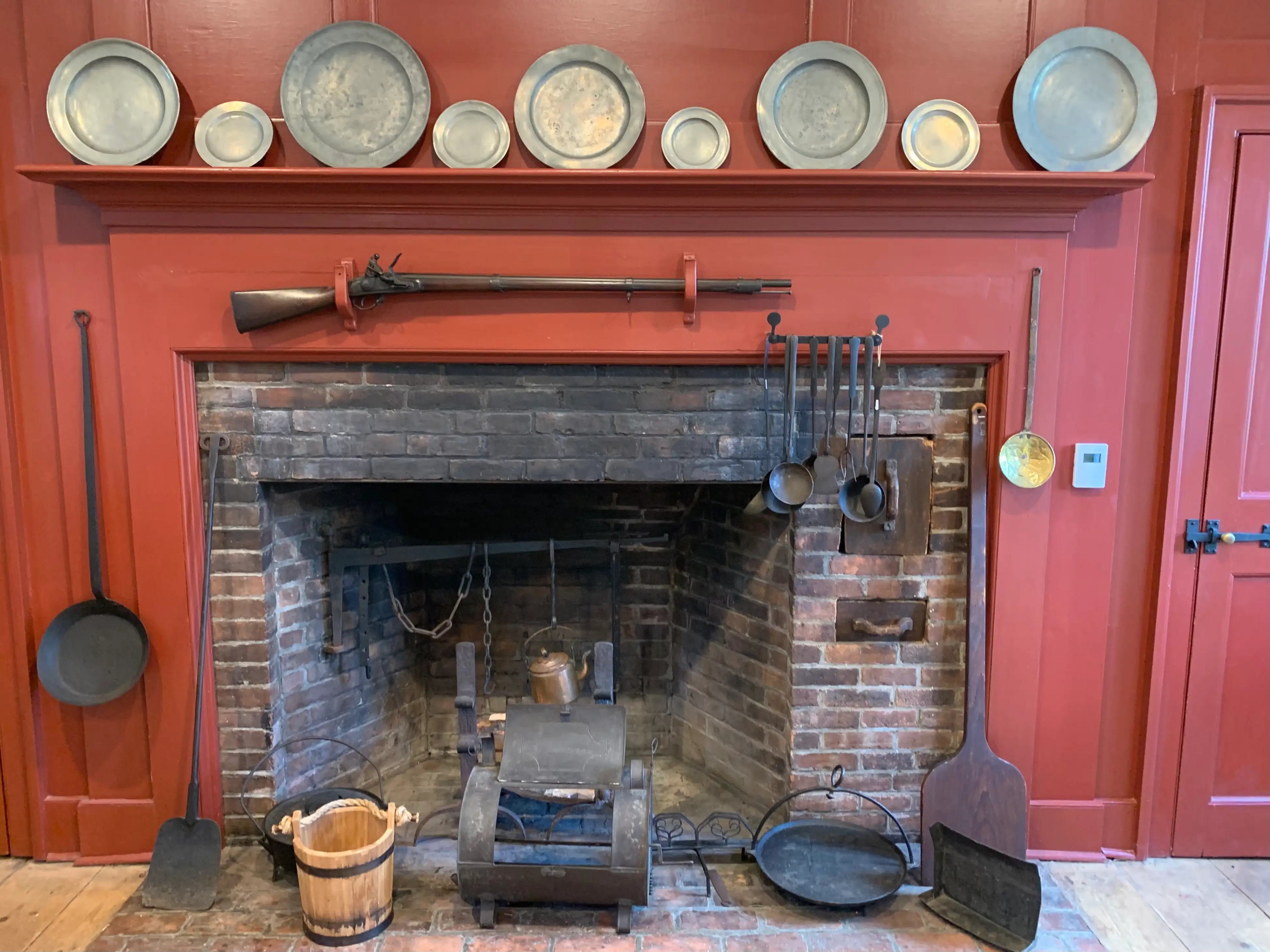 Fireplace in Dey mansion kitchen with plates and a rifle hanging on the wall