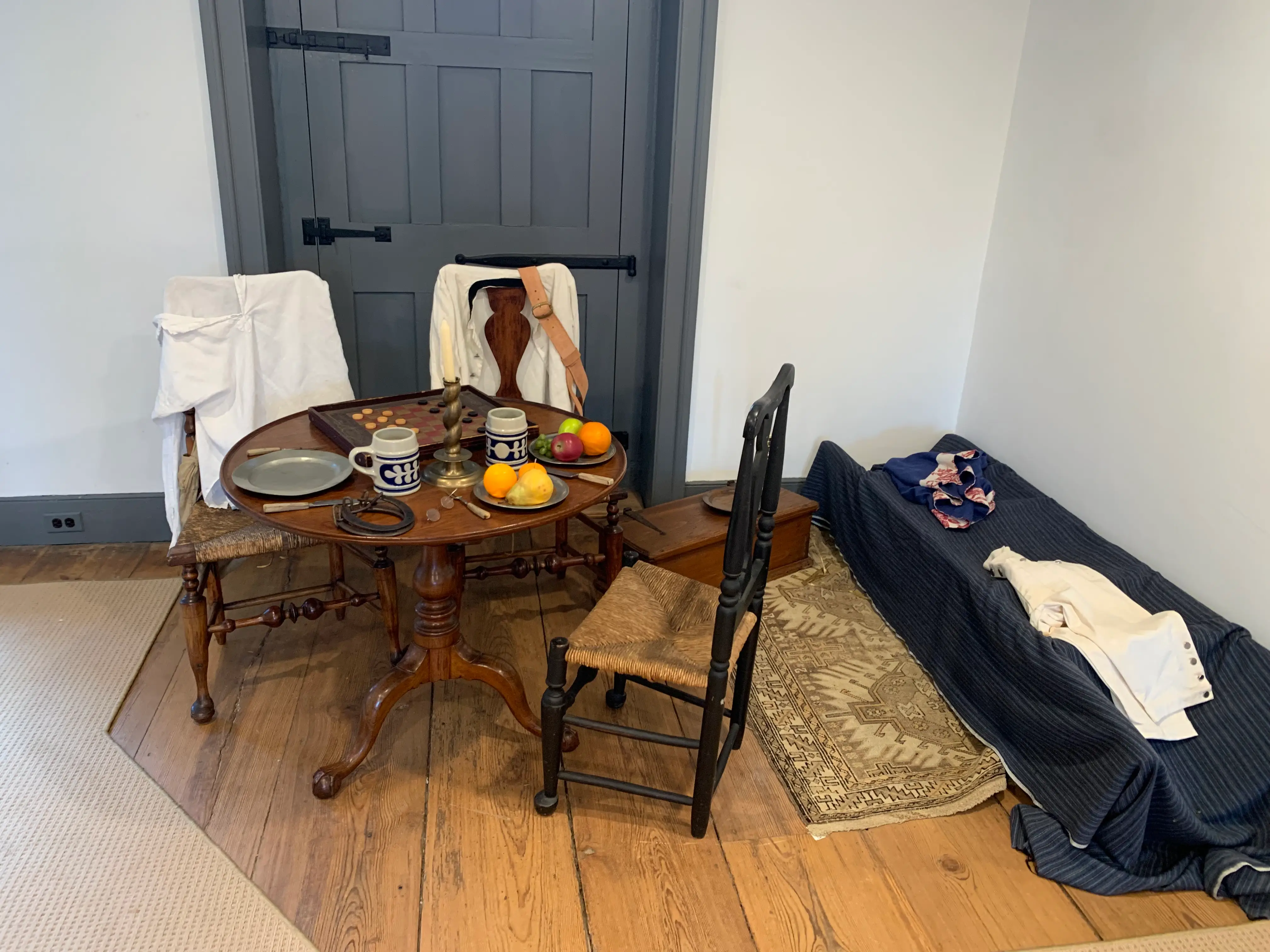 A table with mugs, fruit, and a checkers board on it