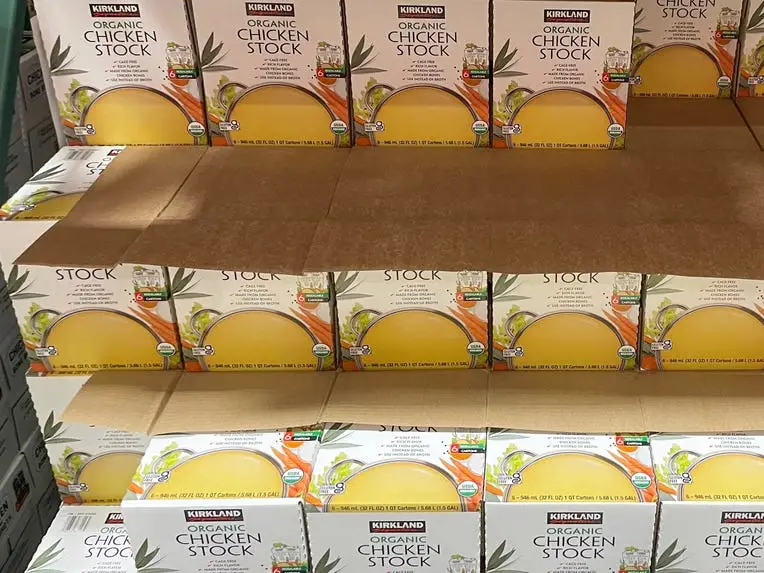 White boxes of Kirkland Signature organic chicken stick with graphics of broth on packaging on shelves