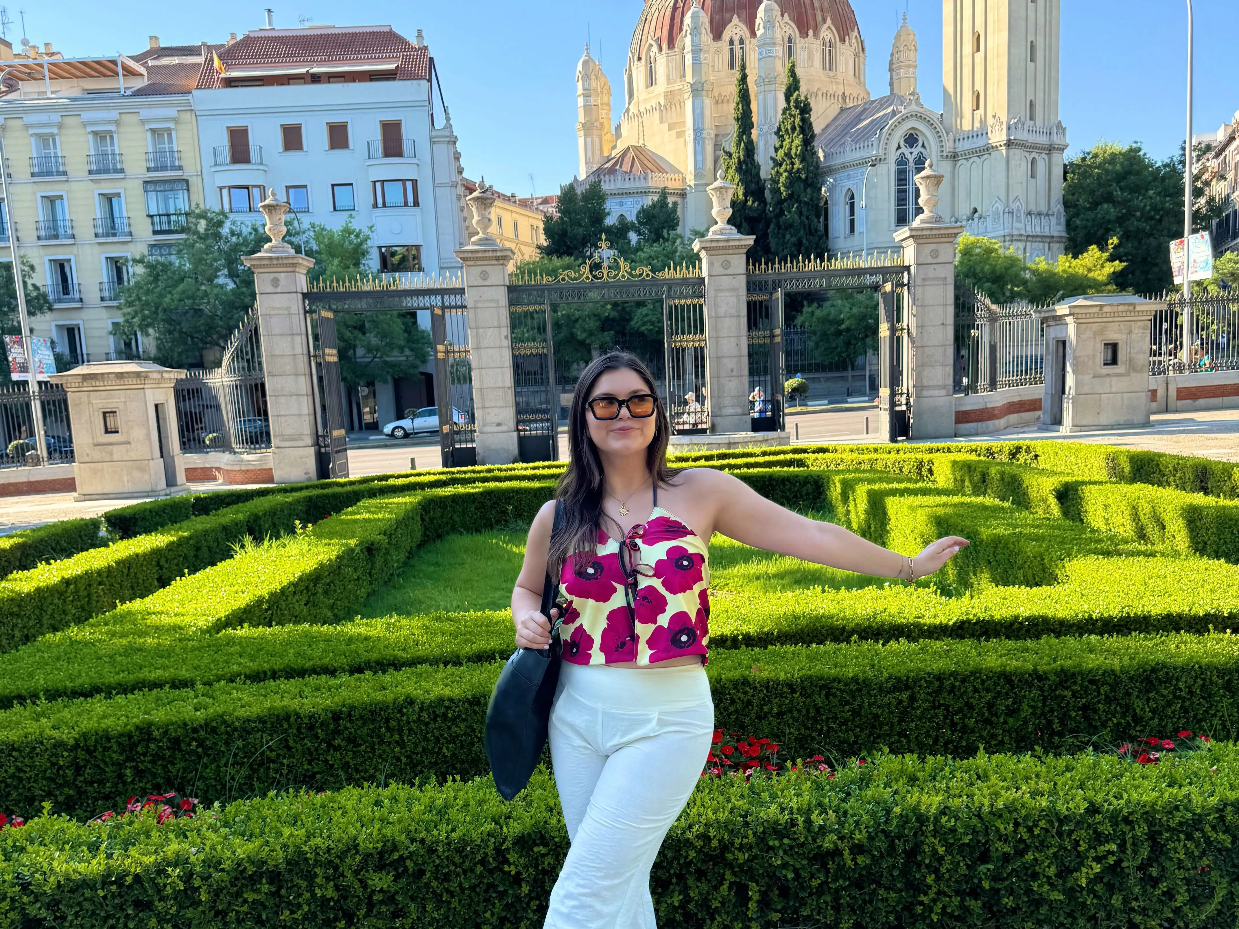 The writer wearing white pants and standing in front of architecture in Madrid, Spain.