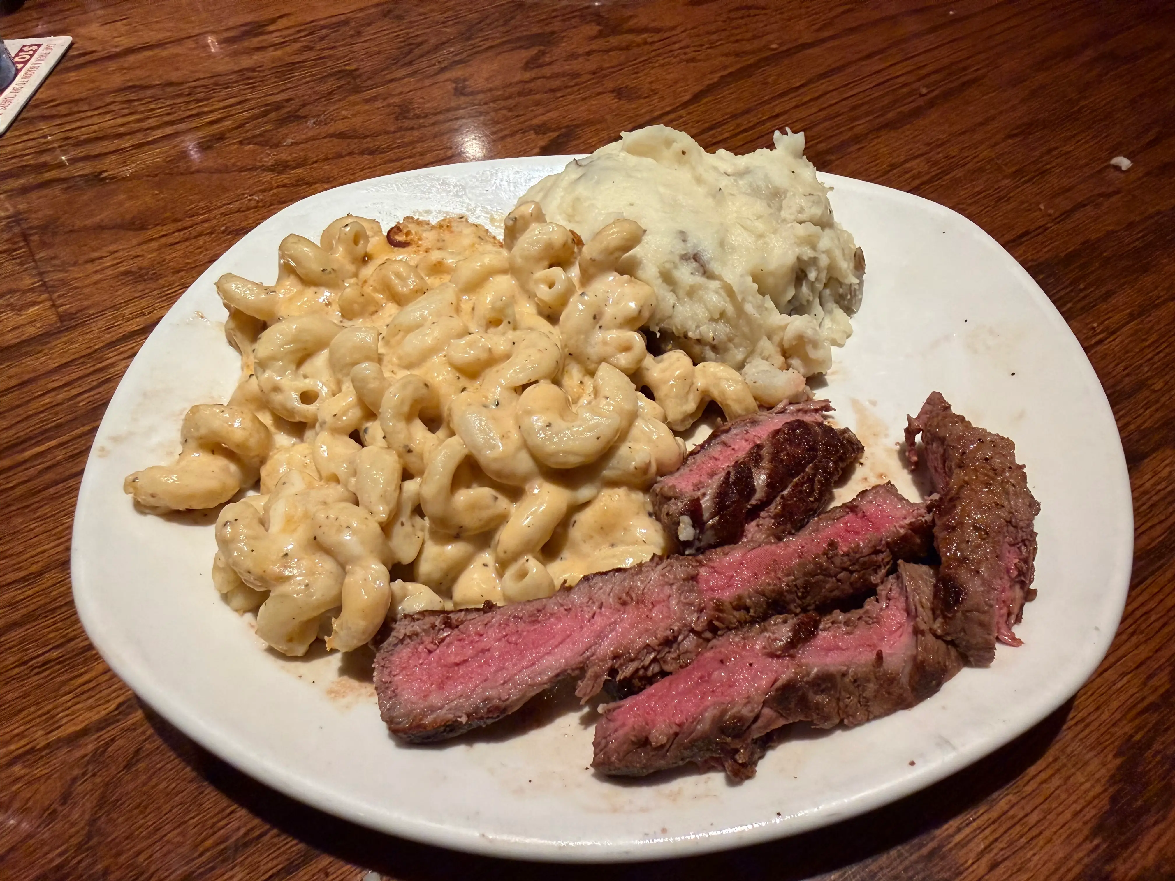 Sliced steak, mashed potatoes, mac and cheese on plate at Outback Steakhouse