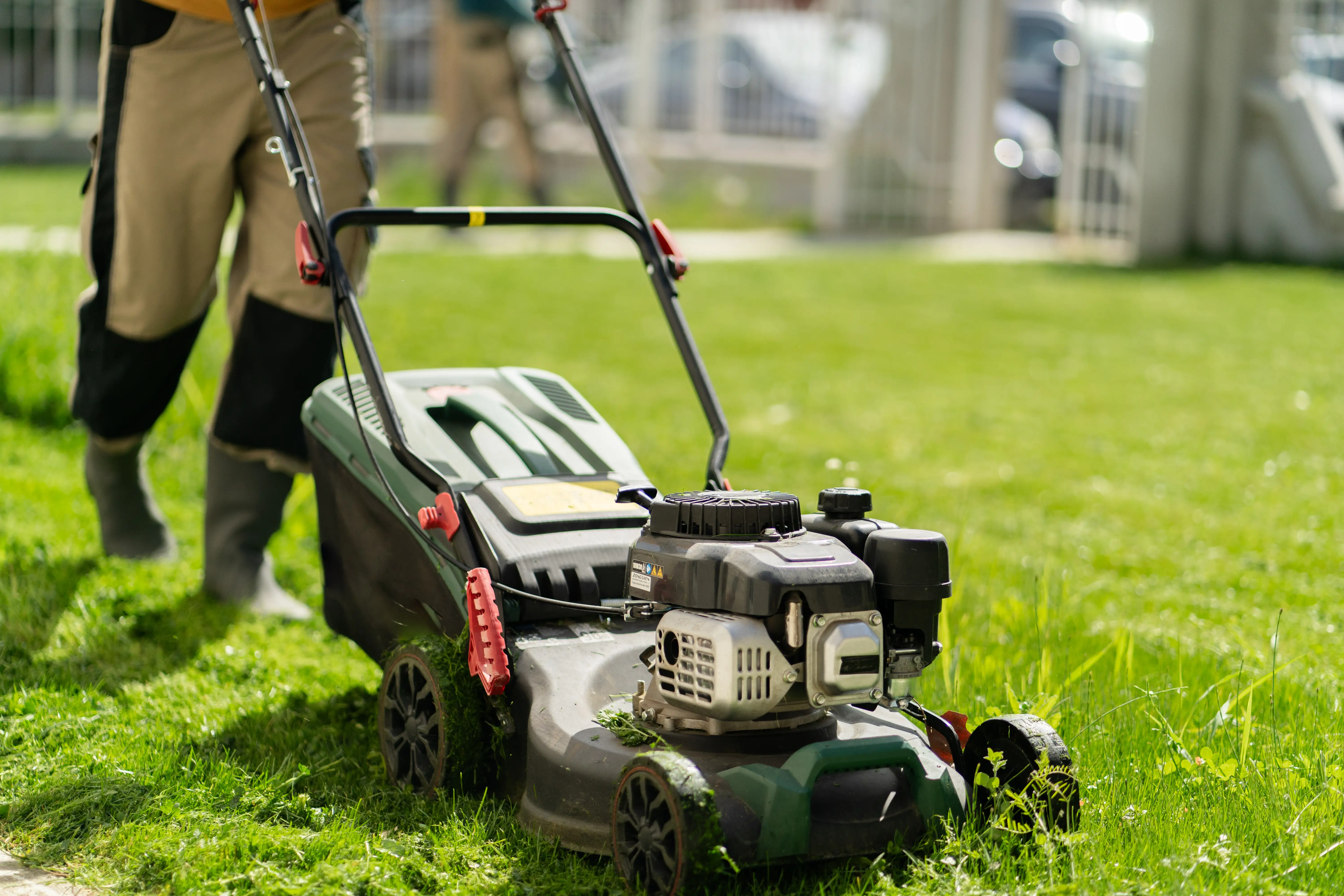 A person pushing a mower in a yard is shown.