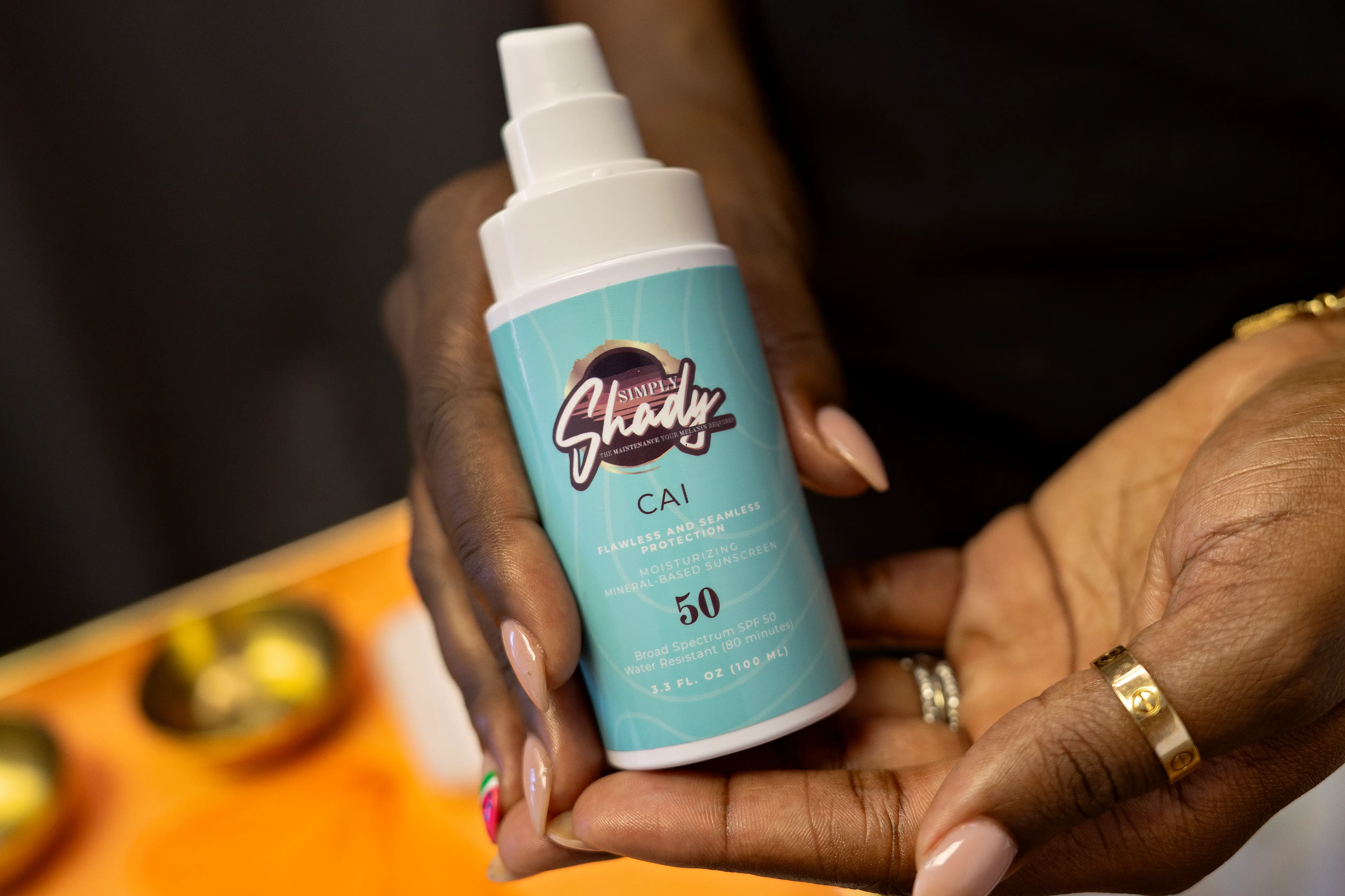 Simone, founder of Queen Aesthetics, holds up a Simply Shady bottle.