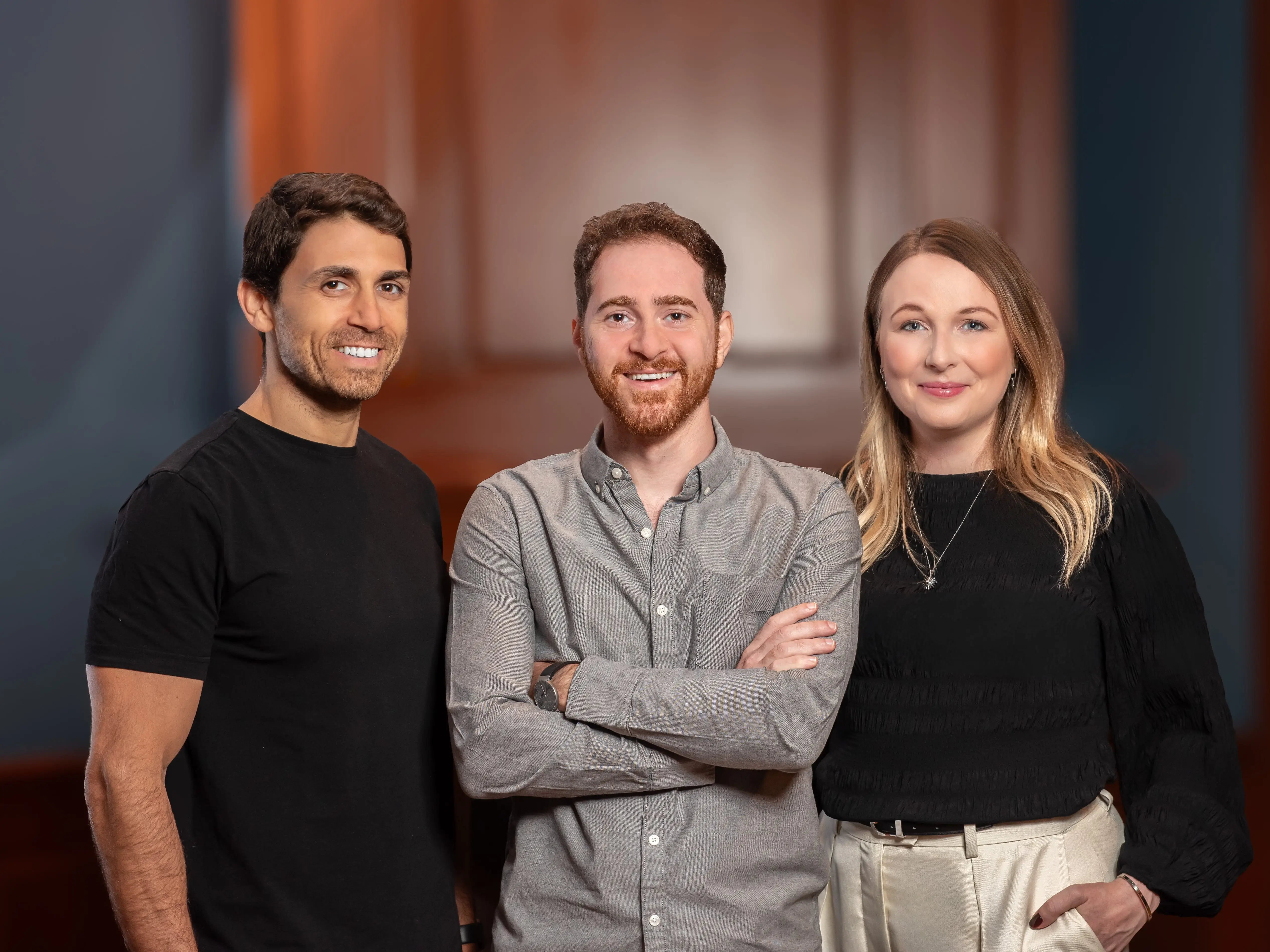 Unframe cofounders standing shoulder to shoulder in front of a wooden door.
