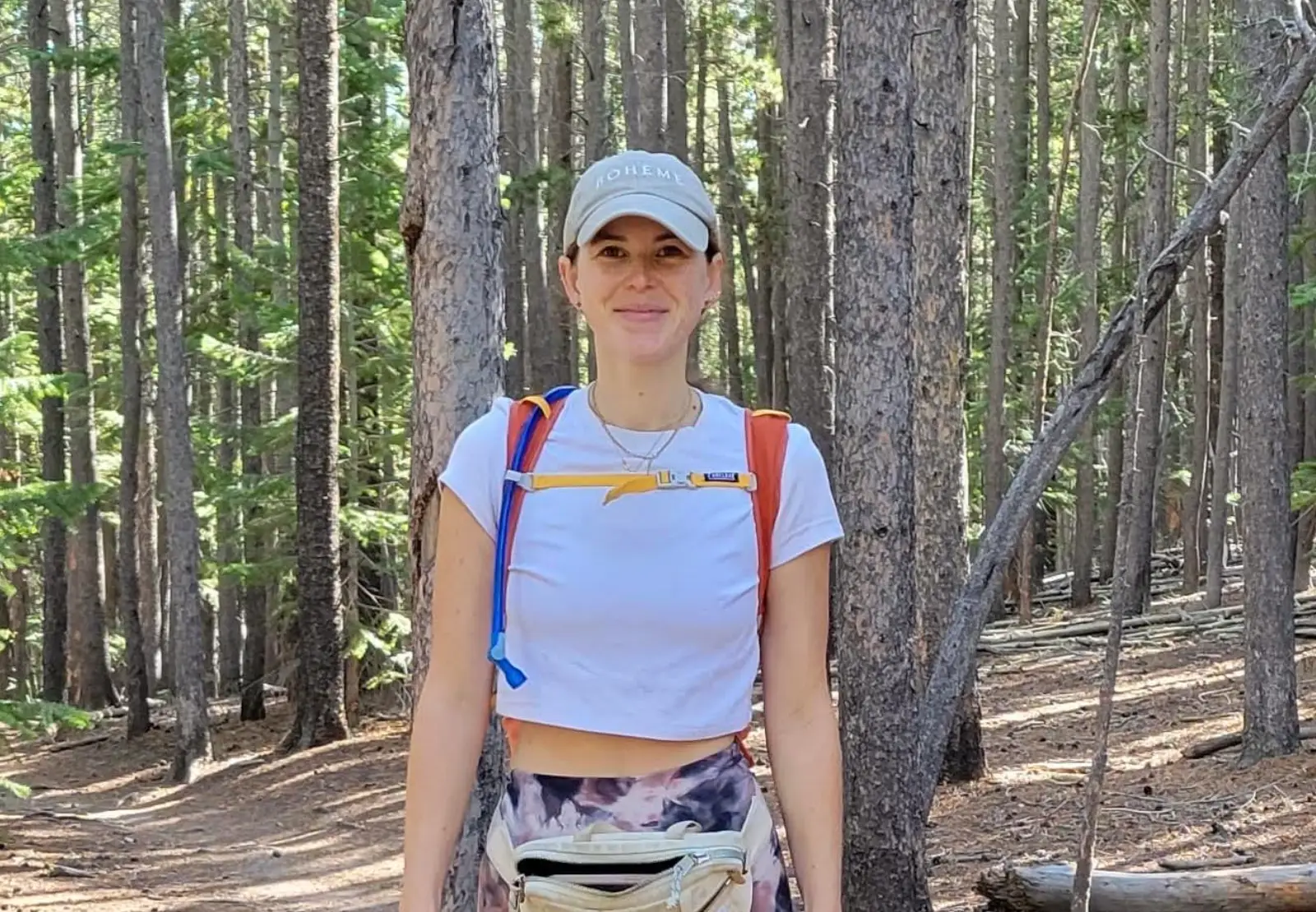 The writer  wearing hiking gear and standing in the woods.