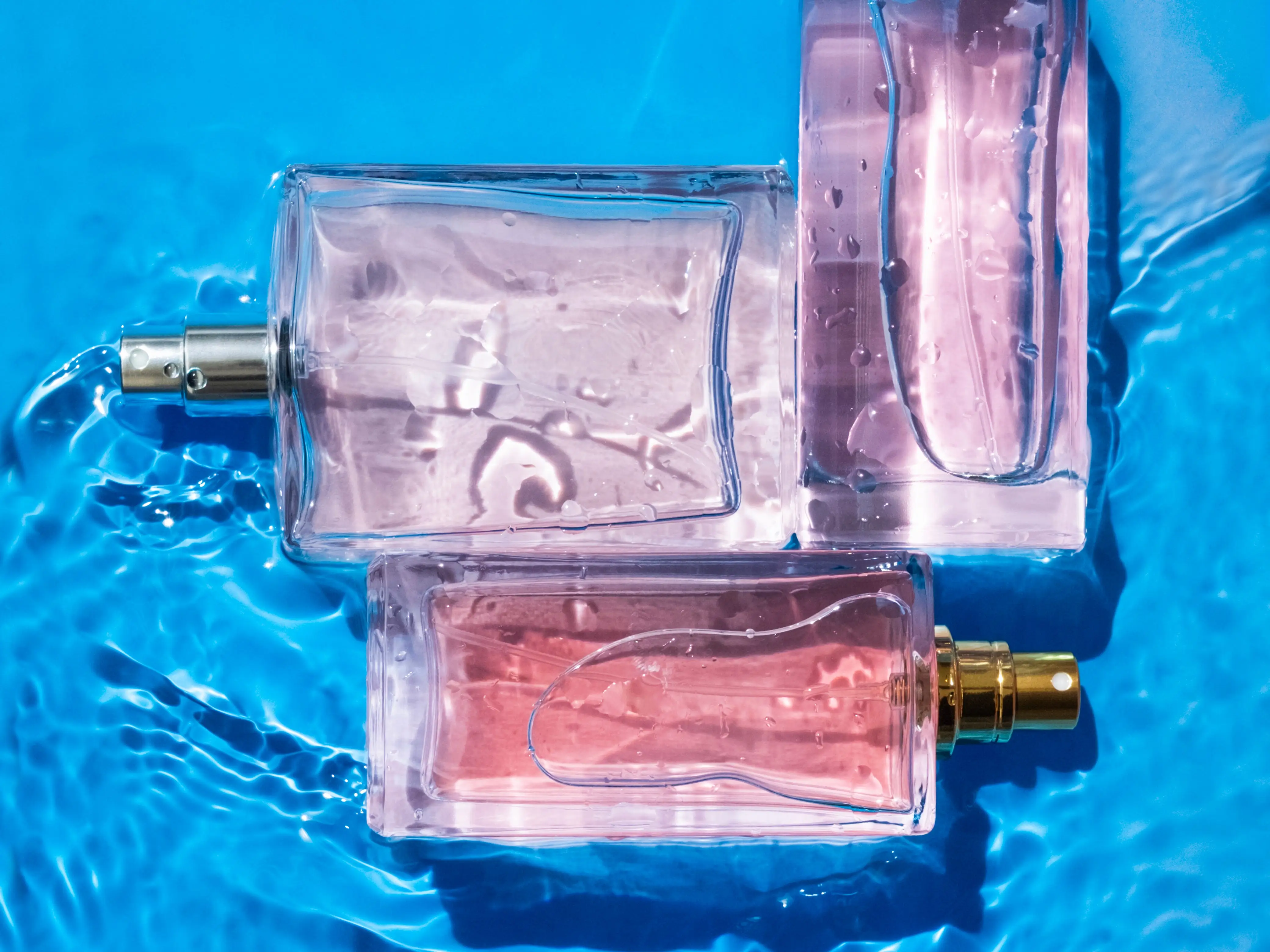 Three perfume bottles submerged in water.