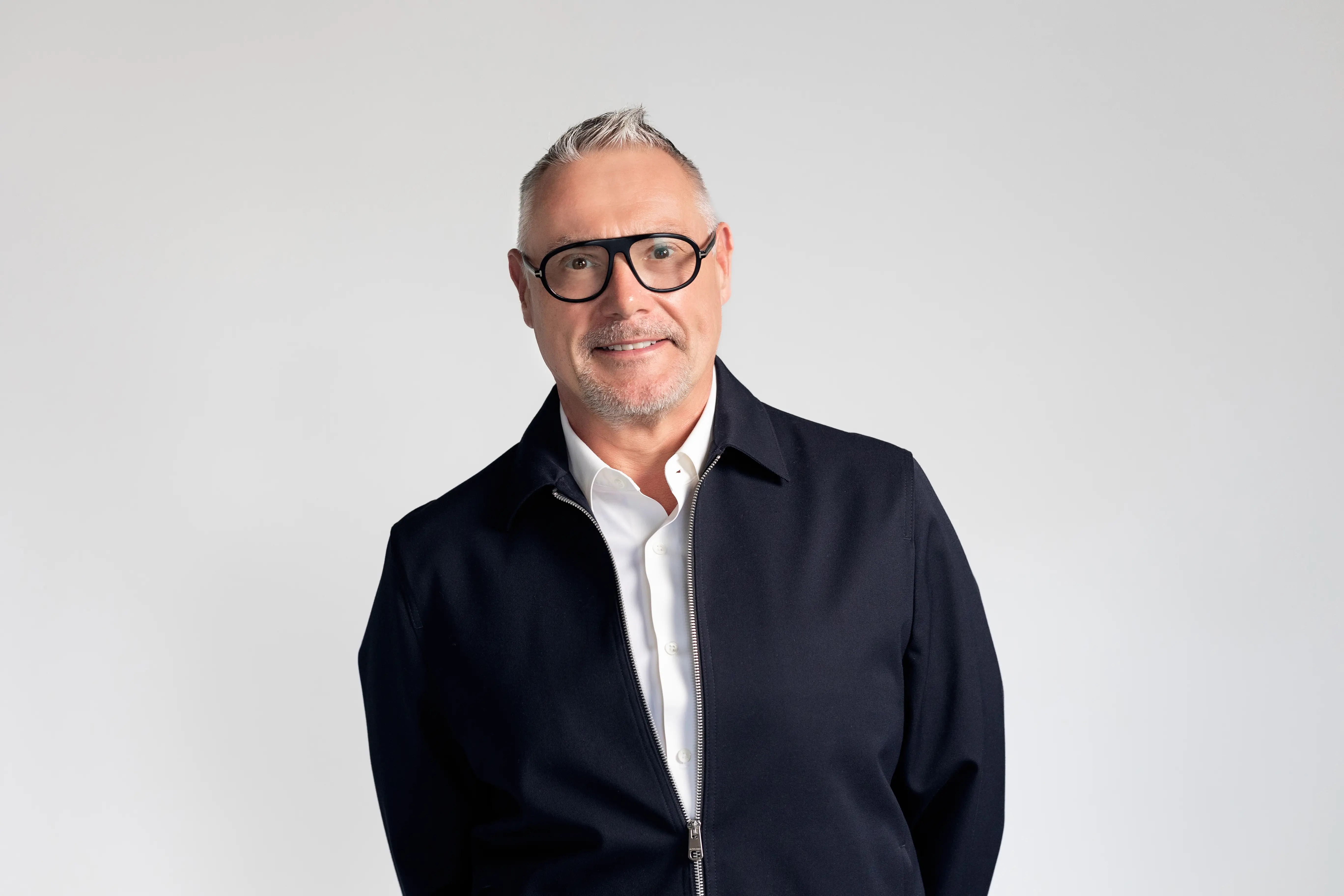 Business headshot of man with glasses, wearing a jacket