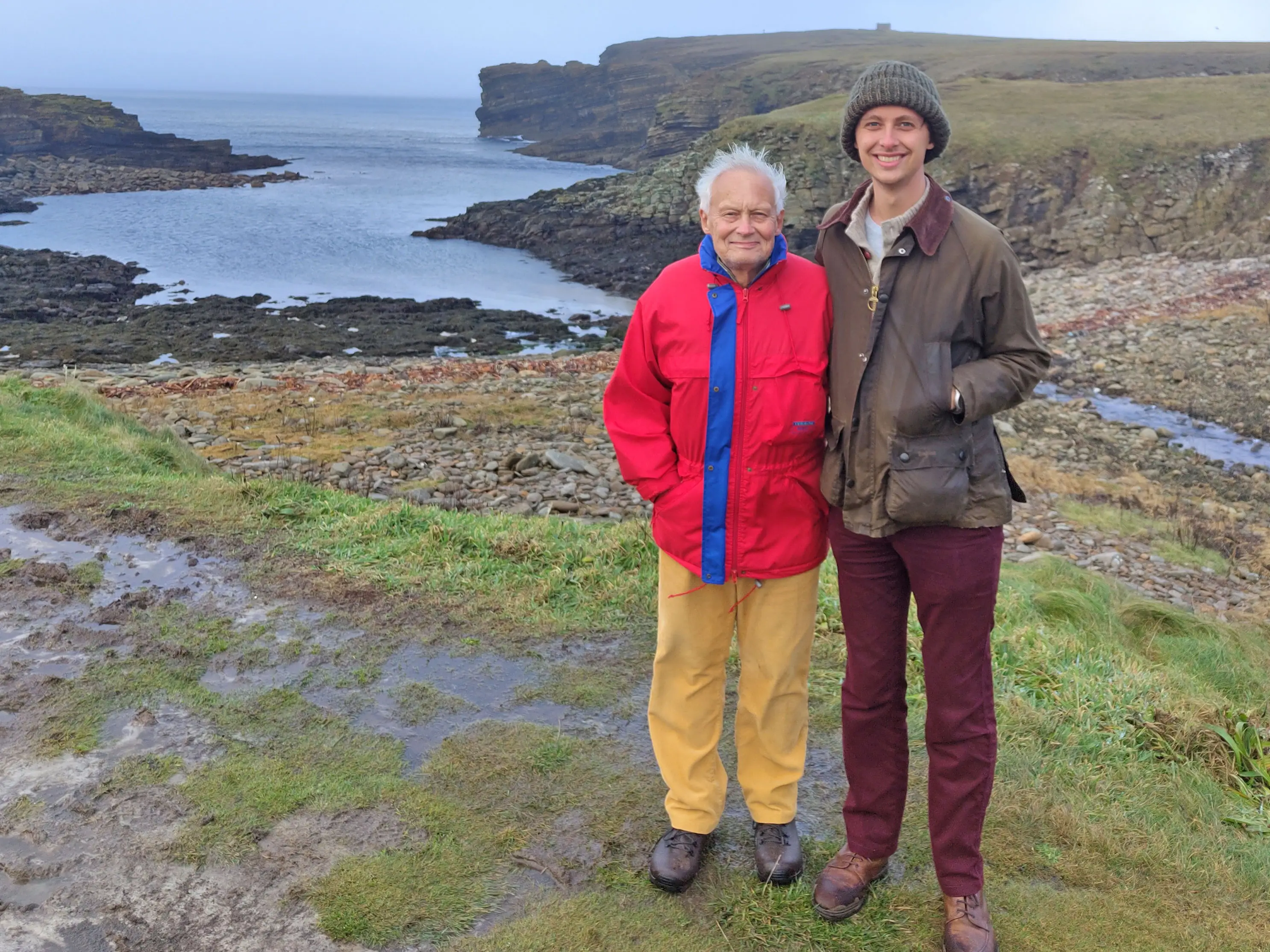 Finn and his son stand near cliffs in the Orkney Islands.