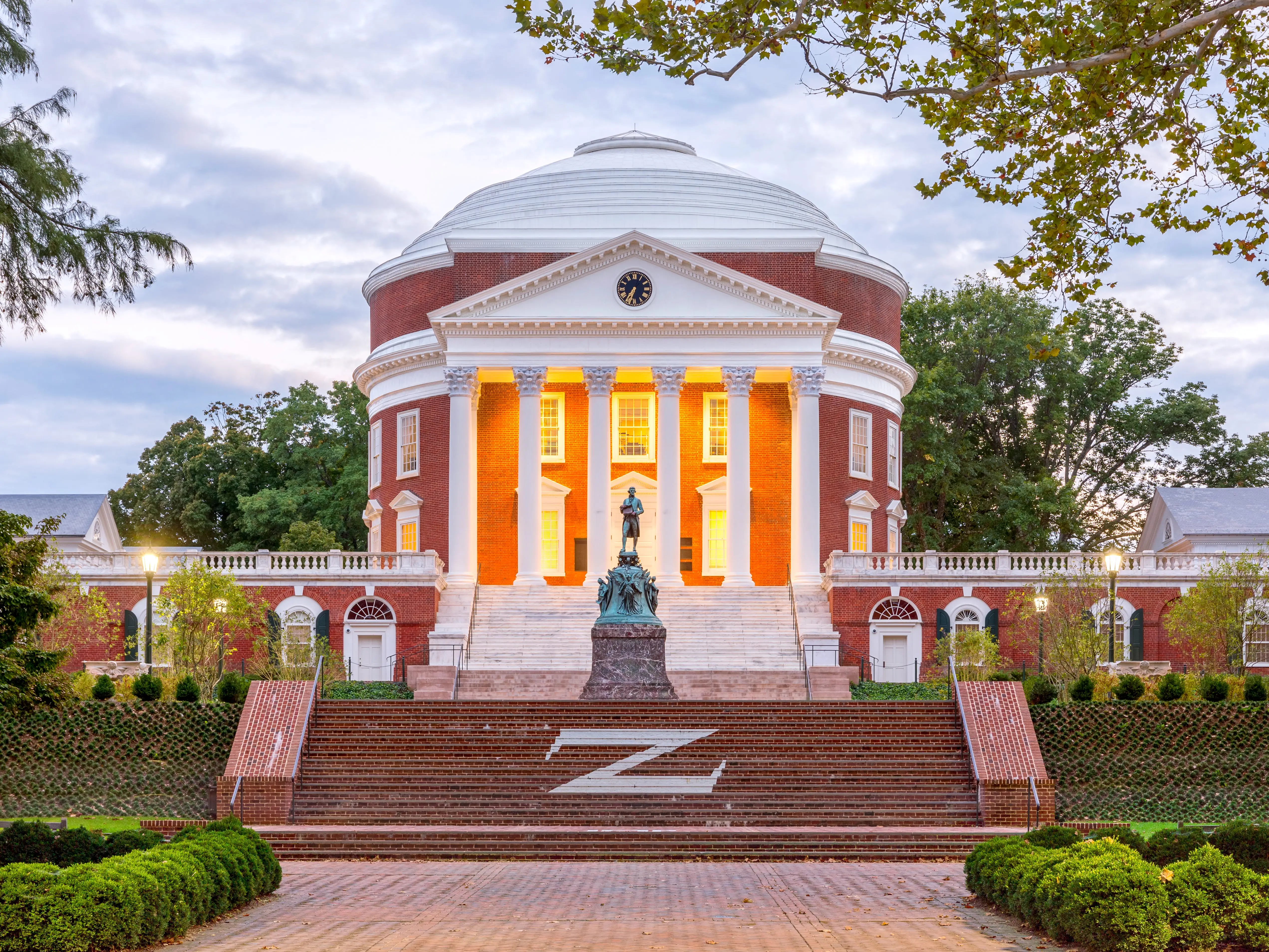 Charlottesville, USA - September 16, 2017: The Rotunda at the University of Virginia at dusk with Thomas Jefferson Statue in the foreground