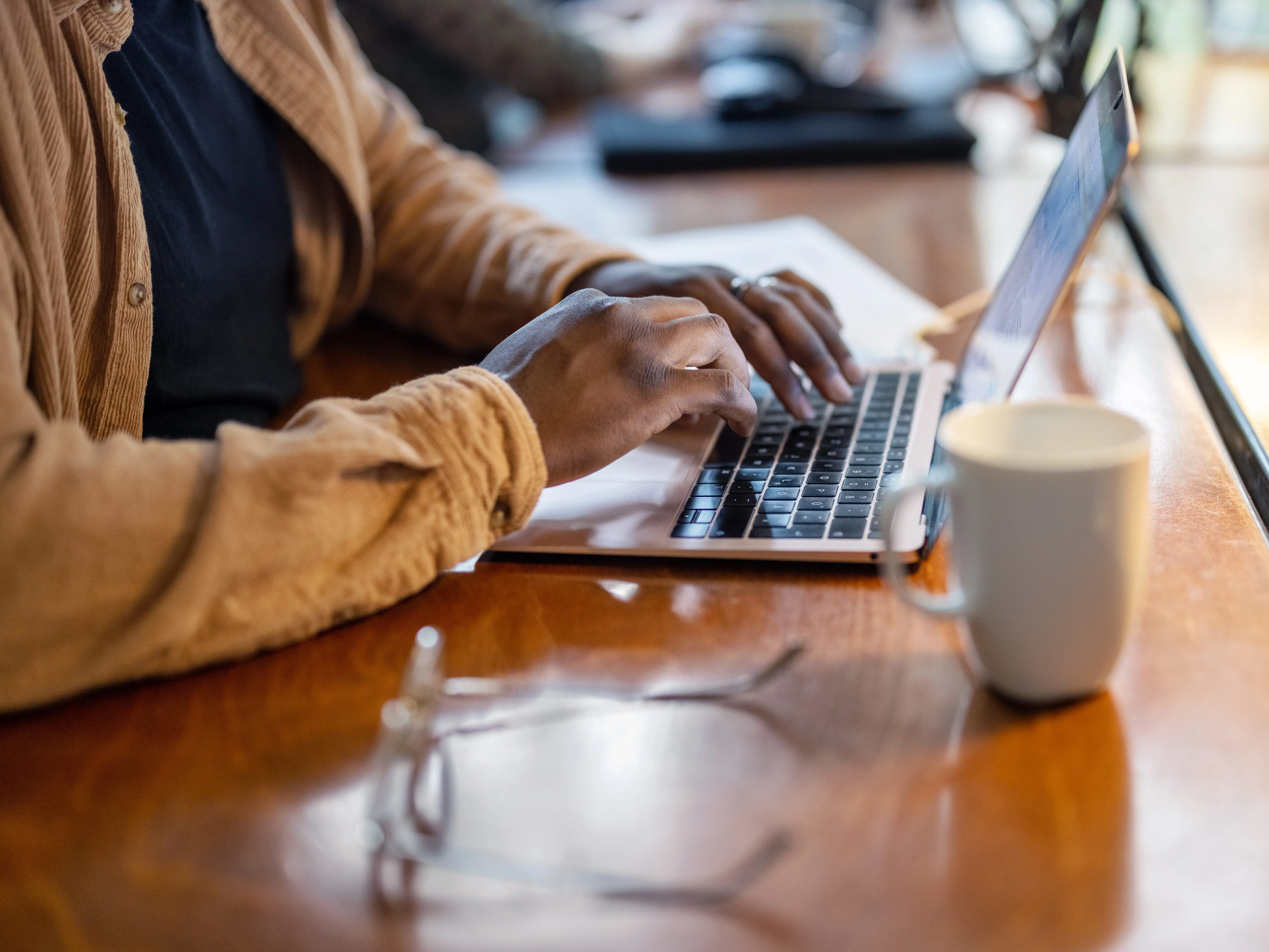 A man working on a laptop while drinking a cup of coffee.