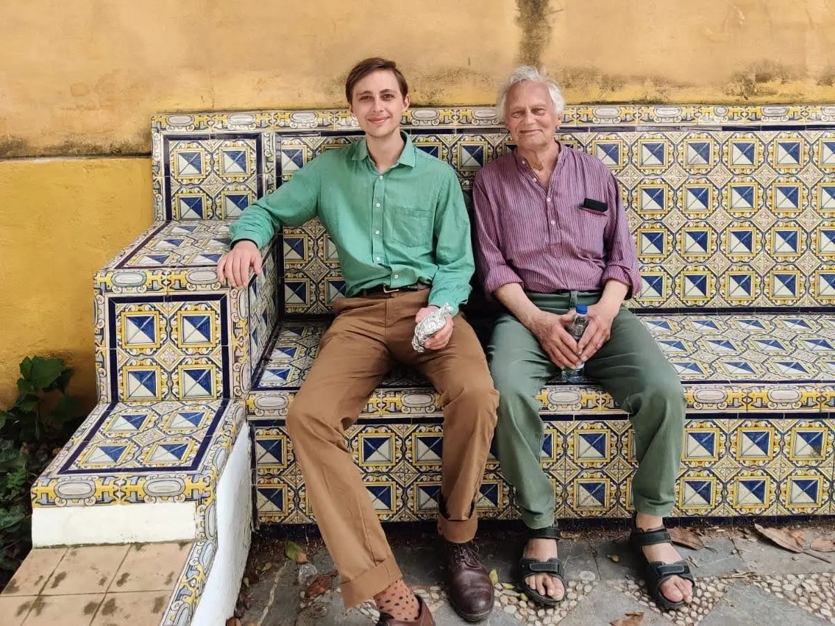 Finn and his son sit on a tiled bench in Spain.
