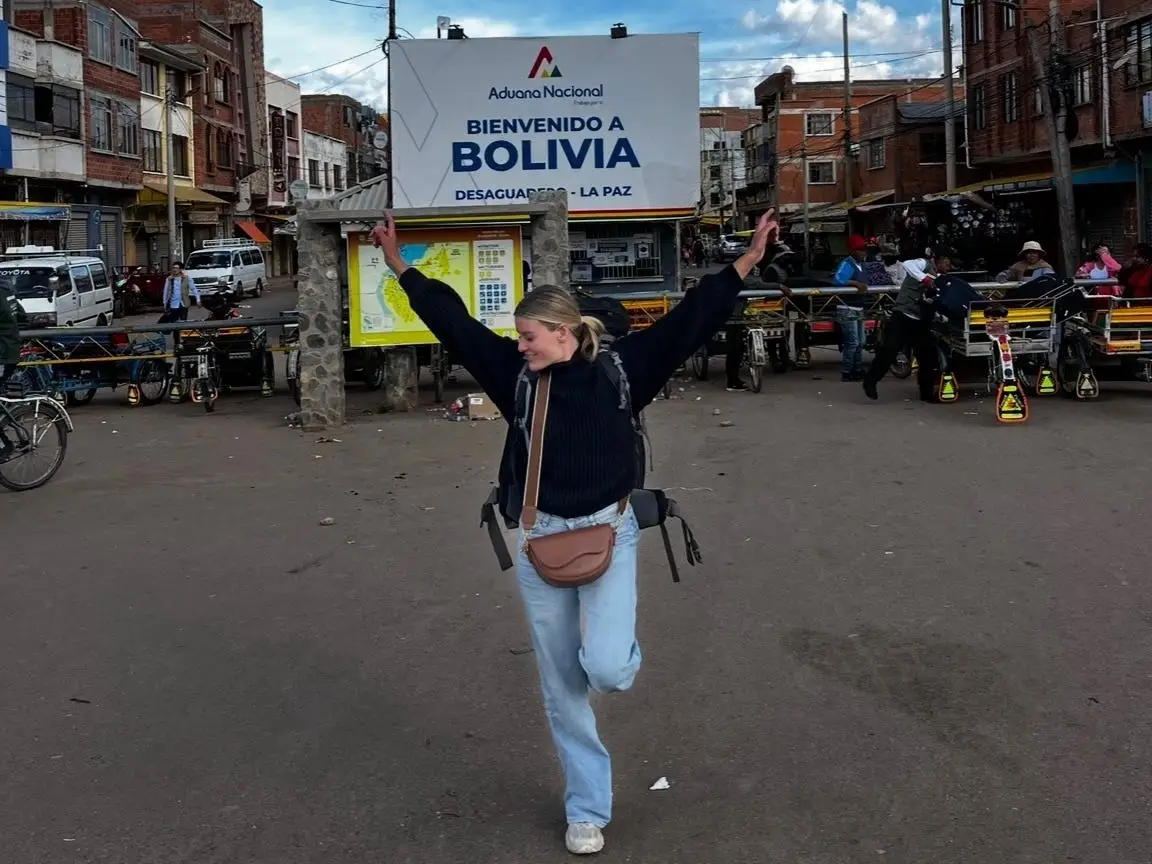 A woman with her arms in the air standing in a Bolivian street.