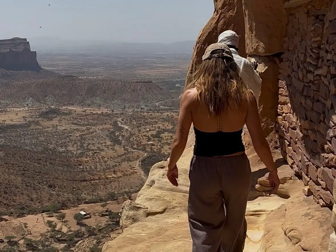 A woman climbing a cliff to Abuna Yemata Guh, a rock-hewn church in Ethiopia.