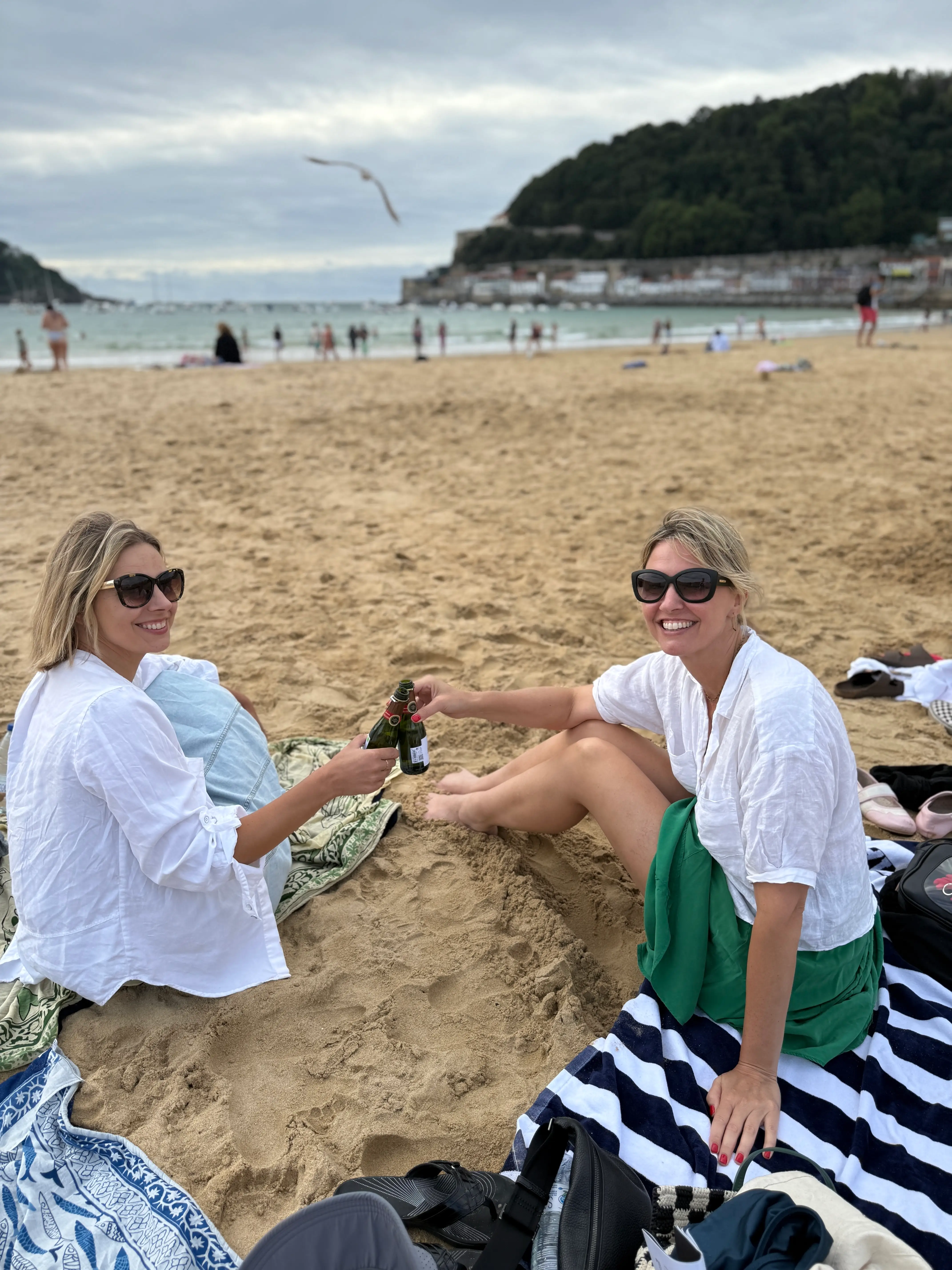 The author clinking beers while sitting on a European beach.