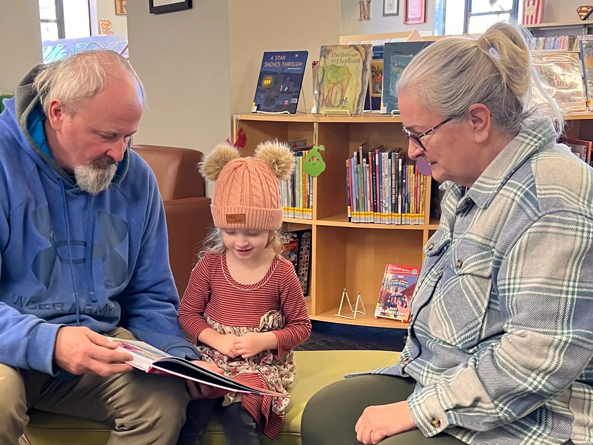 Man holding book next to little girl and woman