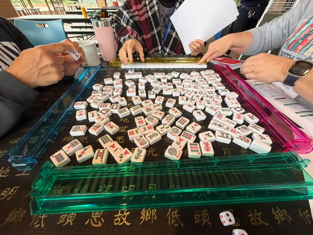 mahjong tiles on a table with three people playing