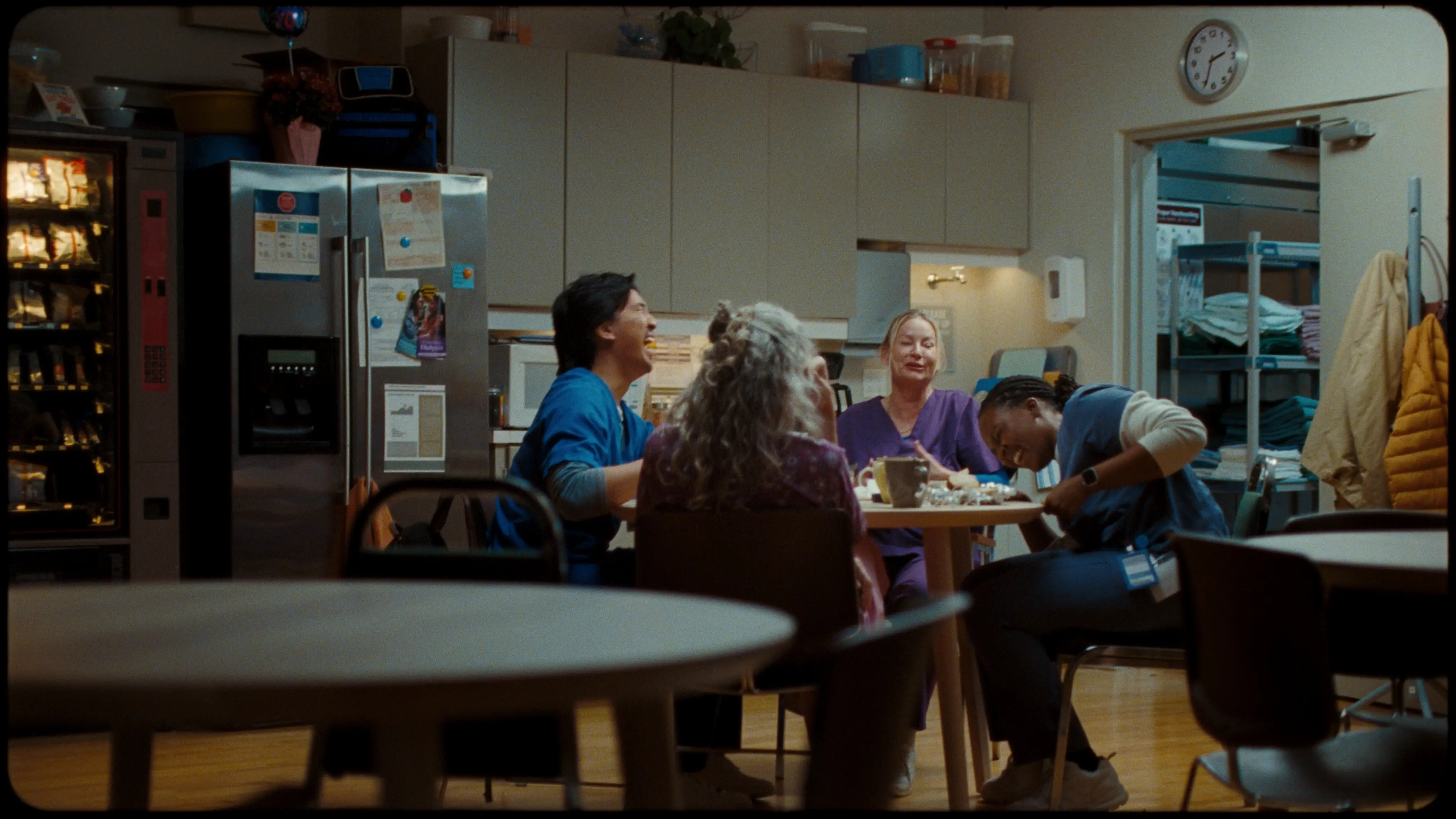Coworkers in a break room laughing around a round table