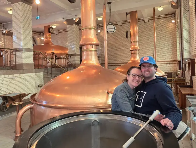 The writer and her partner standing in front of a vat of beer at the Heineken Experience.