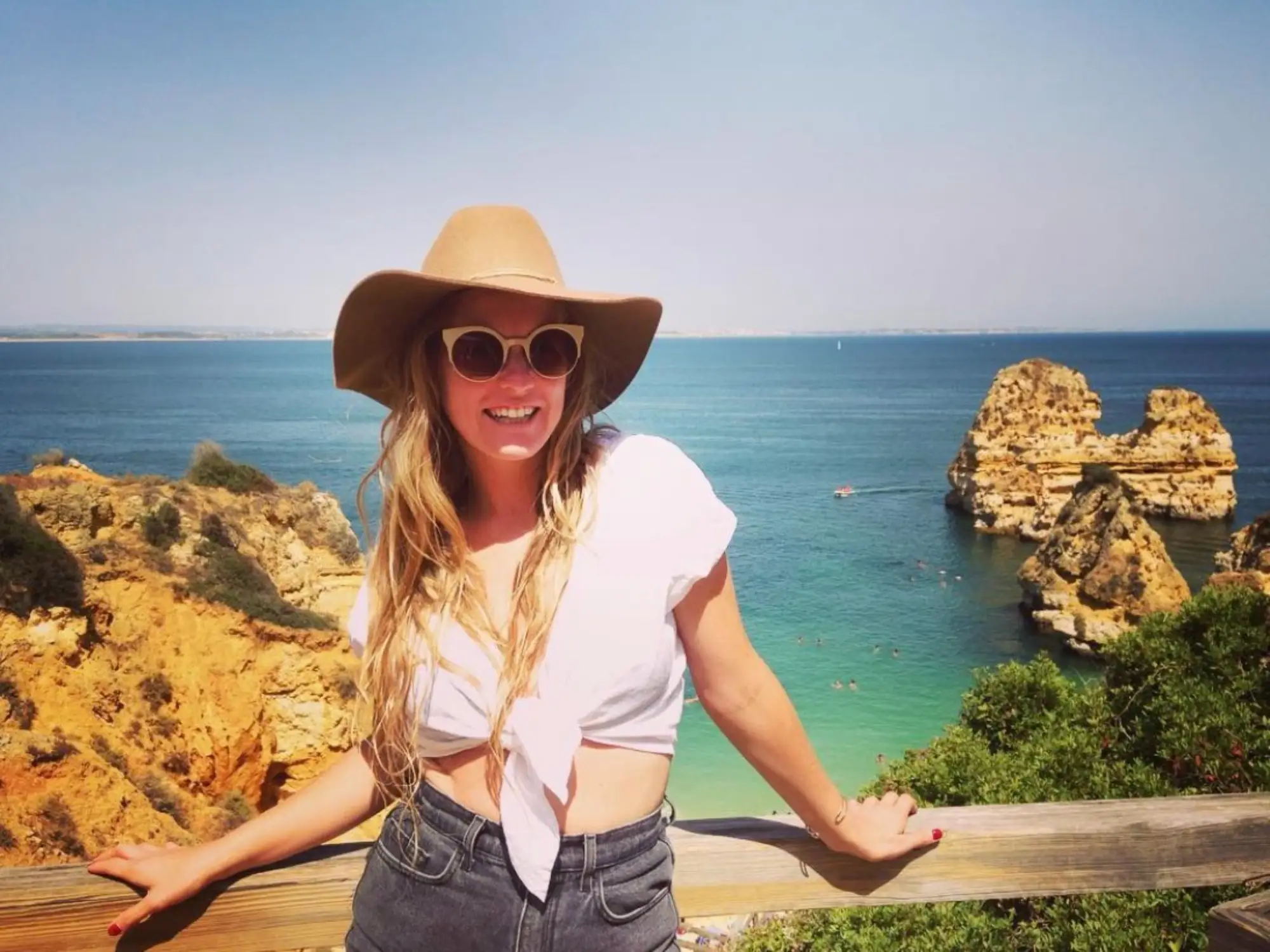 Woman with hat, sunglasses smiling in Lagos Portugal