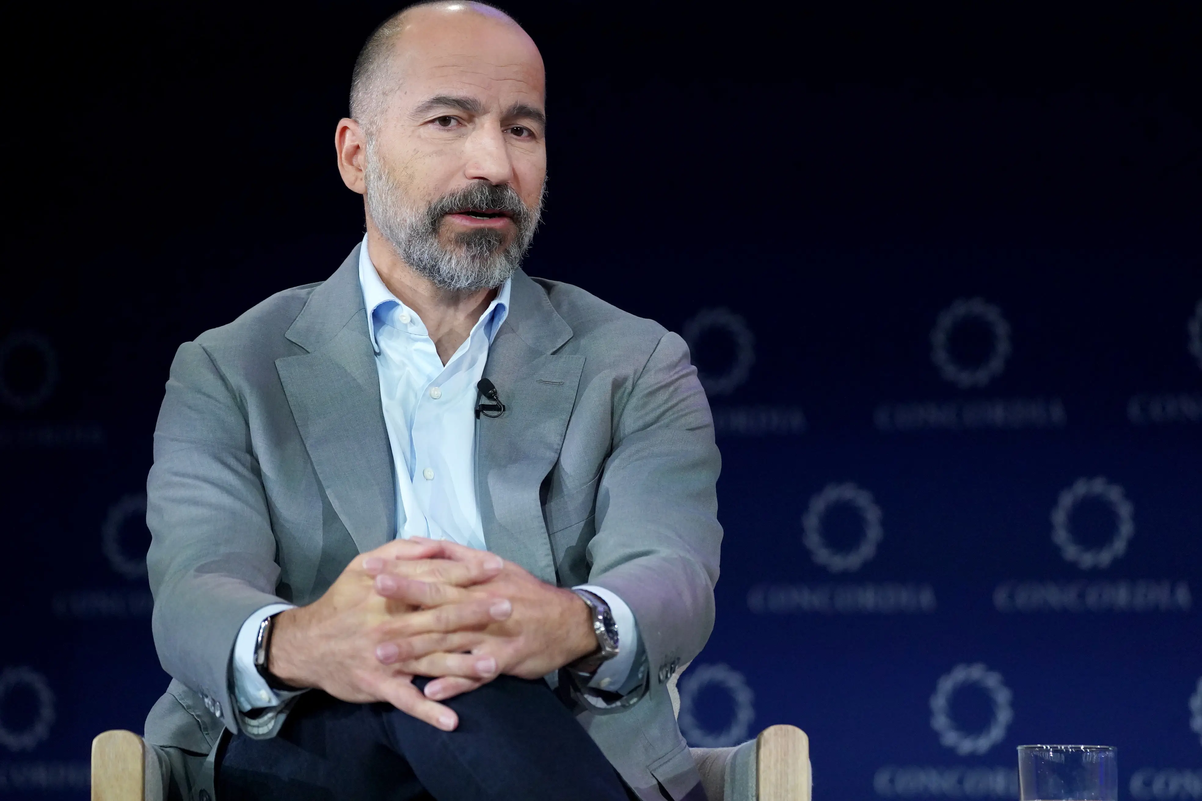 Uber CEO Dara Khosrowshahi speaks while seated on stage while wearing a light grey sport coat and a light blue dress shirt.