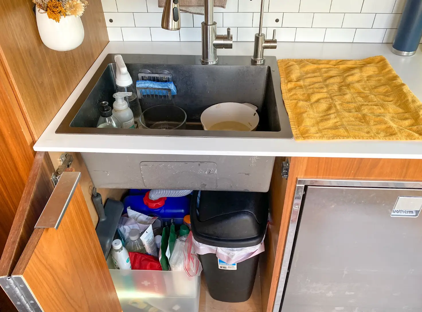 The kitchen in the writer's van, including cleaning products, dishes, and a trash can.