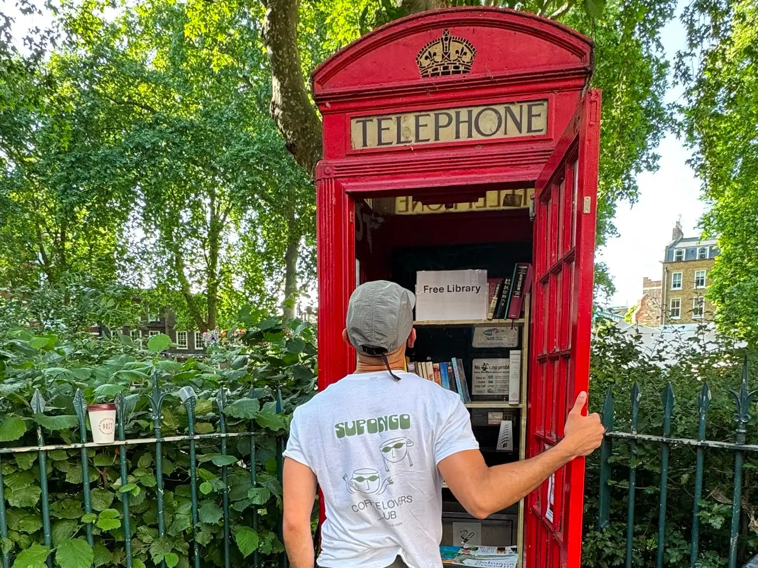 Santiago Barraza Lopez looking inside a london phone booth, which is filled with books