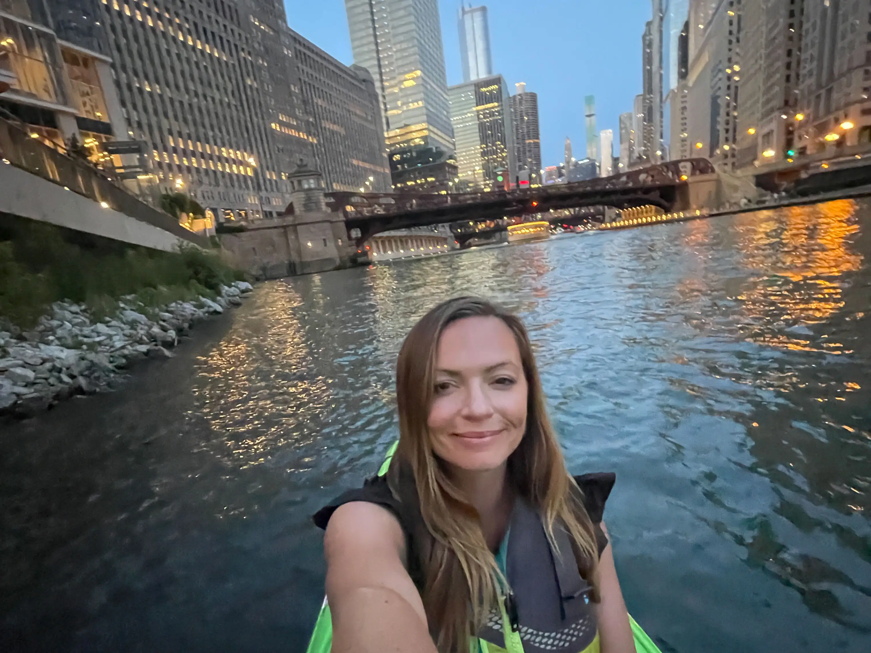 Emily kayaks down a river in downtown Chicago at dusk.