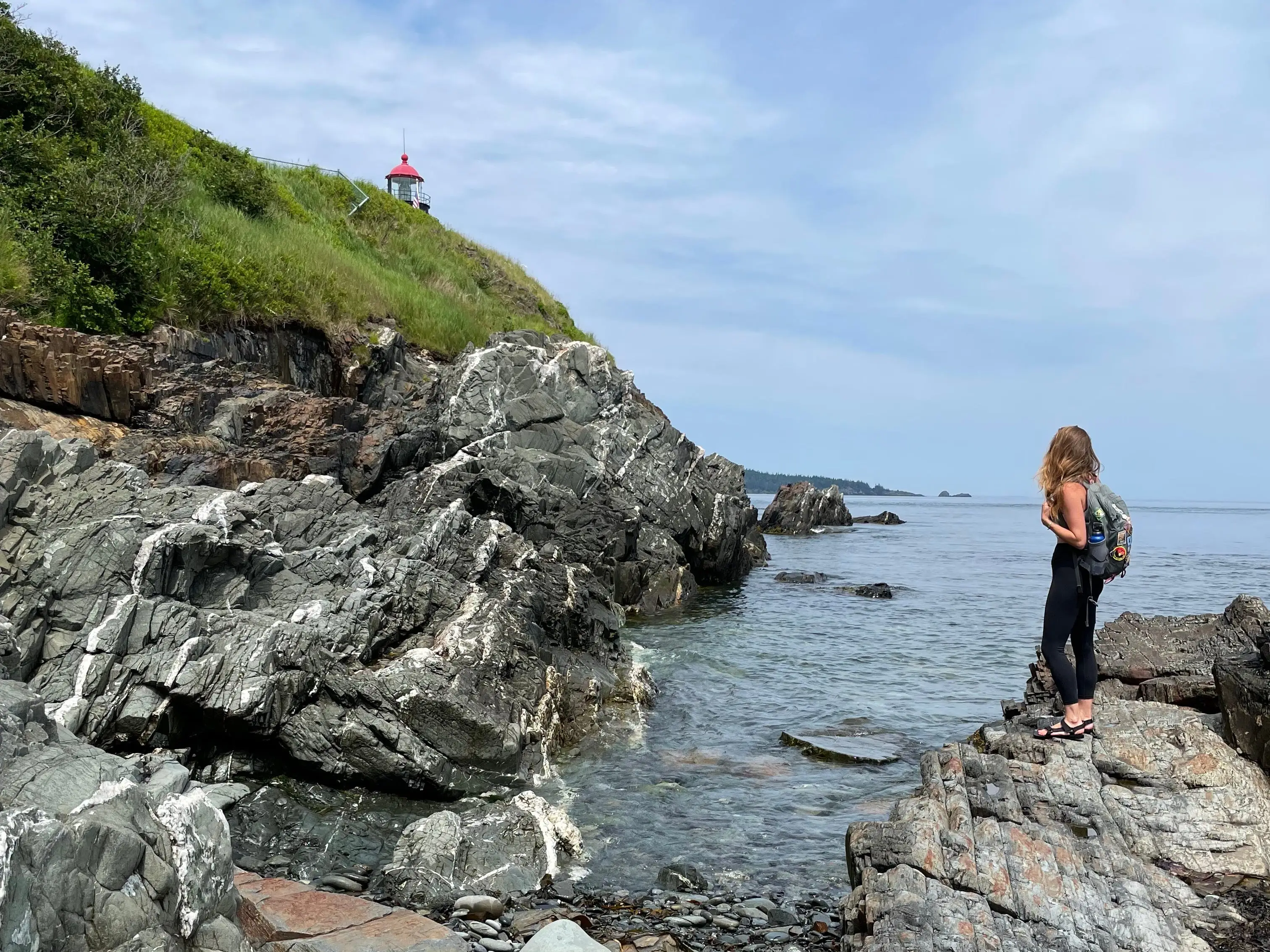 Emily stands on rocks on the coast of Maine.