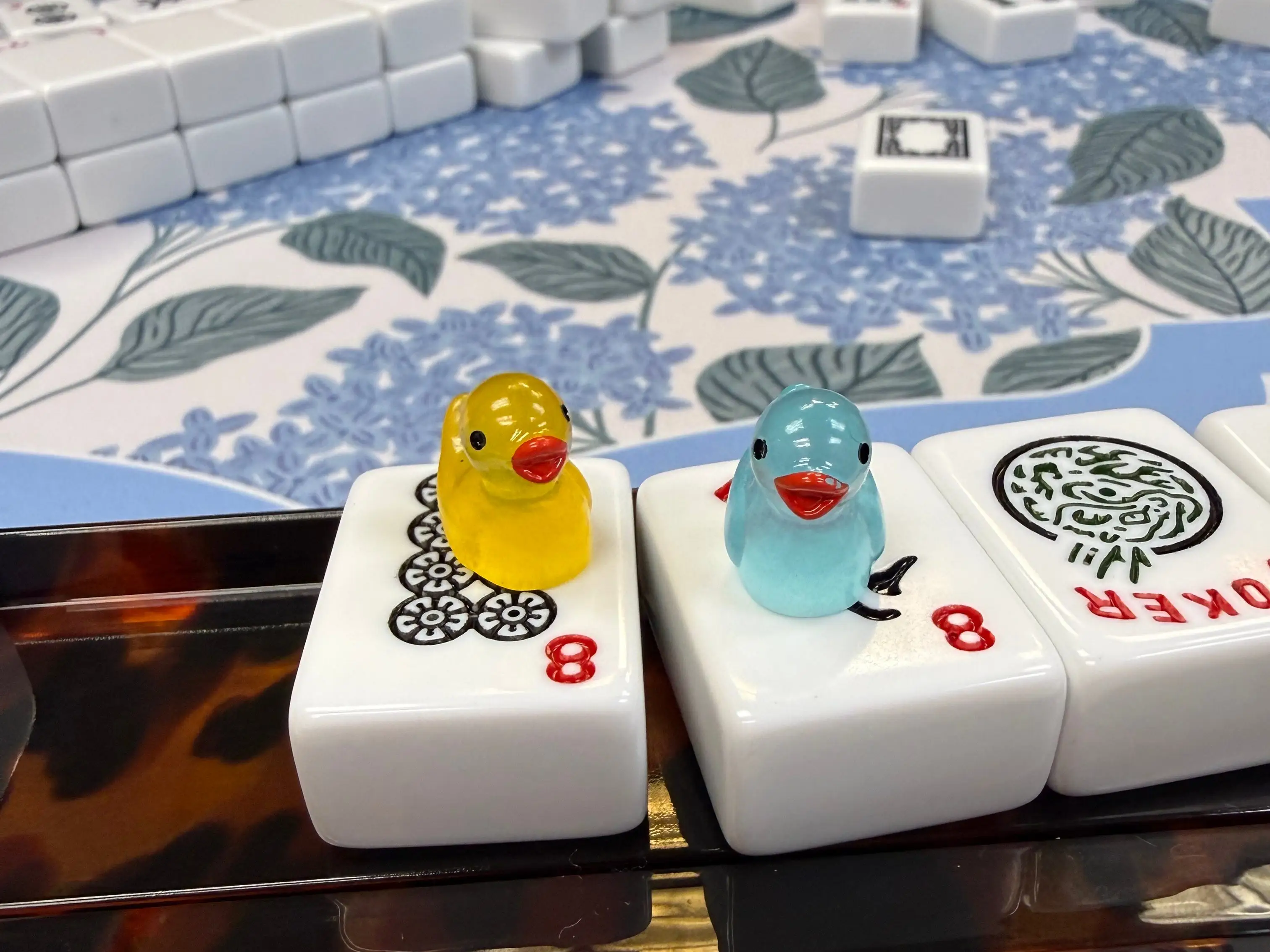 Little tiny blue and yellow ducks on top of Mahjong tiles.