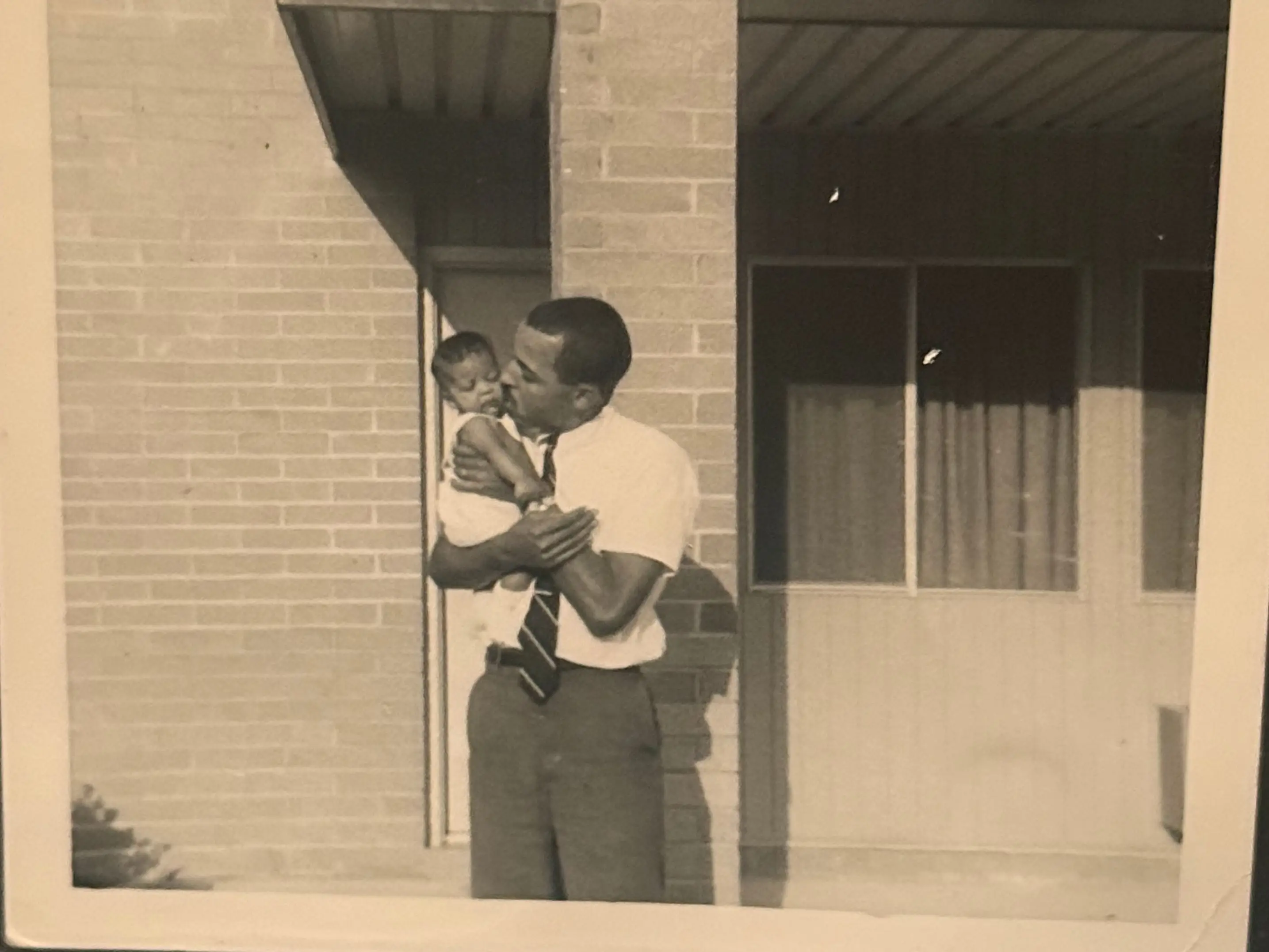 A black and white photo of a man kissing his baby daughter.