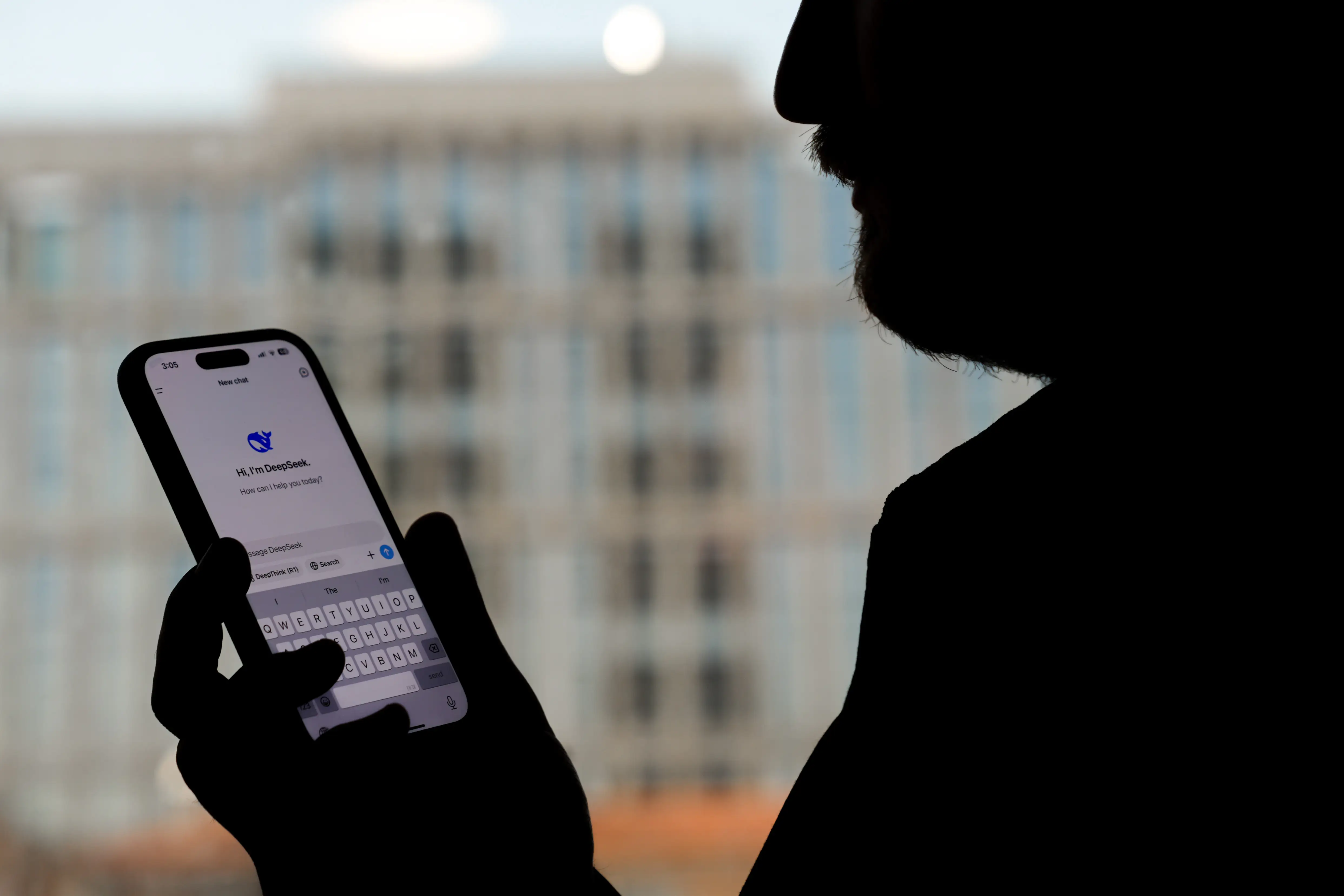 A view of a silhouette of a person holding a smartphone displaying the 'deepseek' application in Ankara, Turkiye, in January 2025.