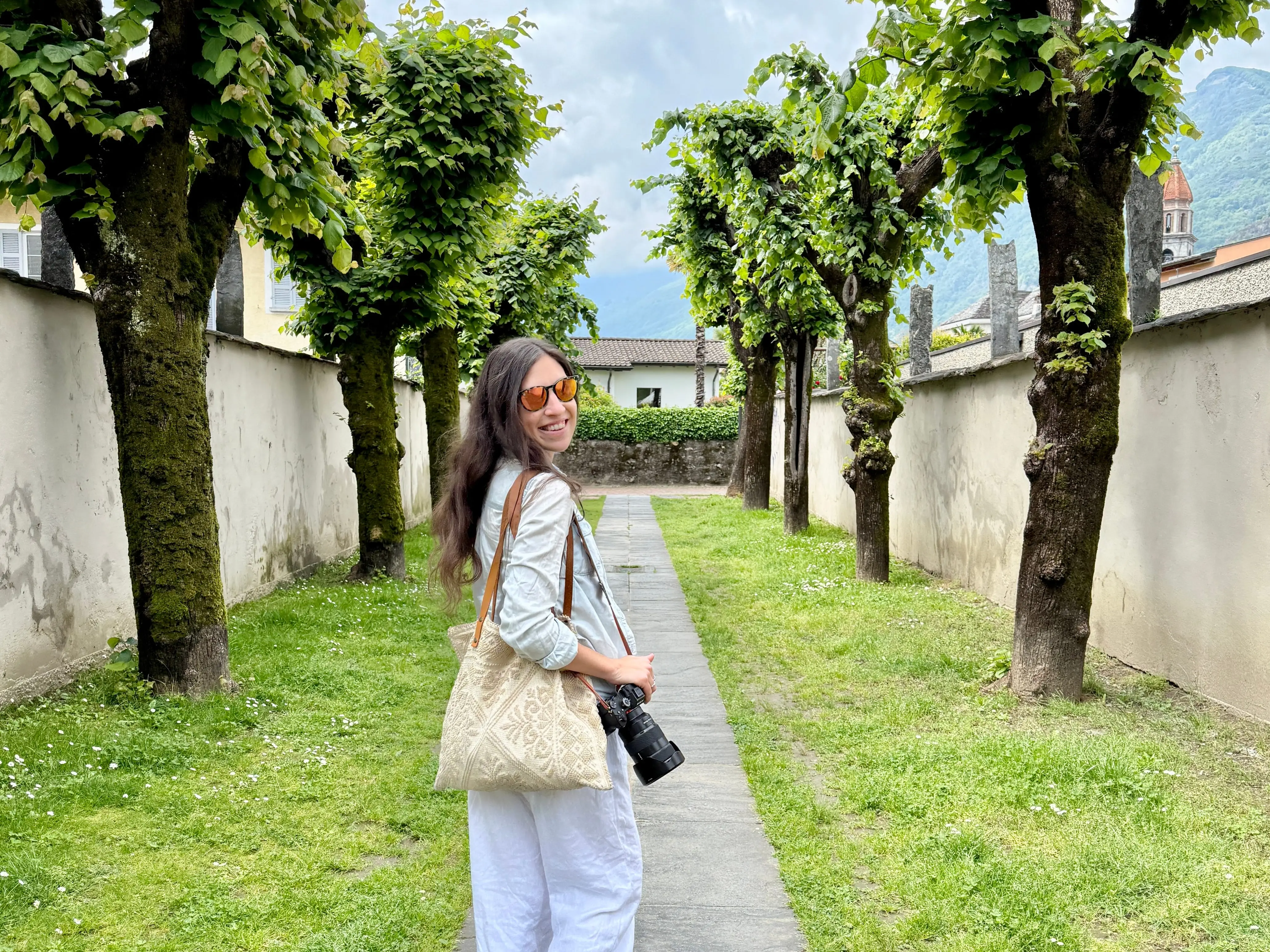 Woman walking on path between grass, trees in Ticino, Switzerland