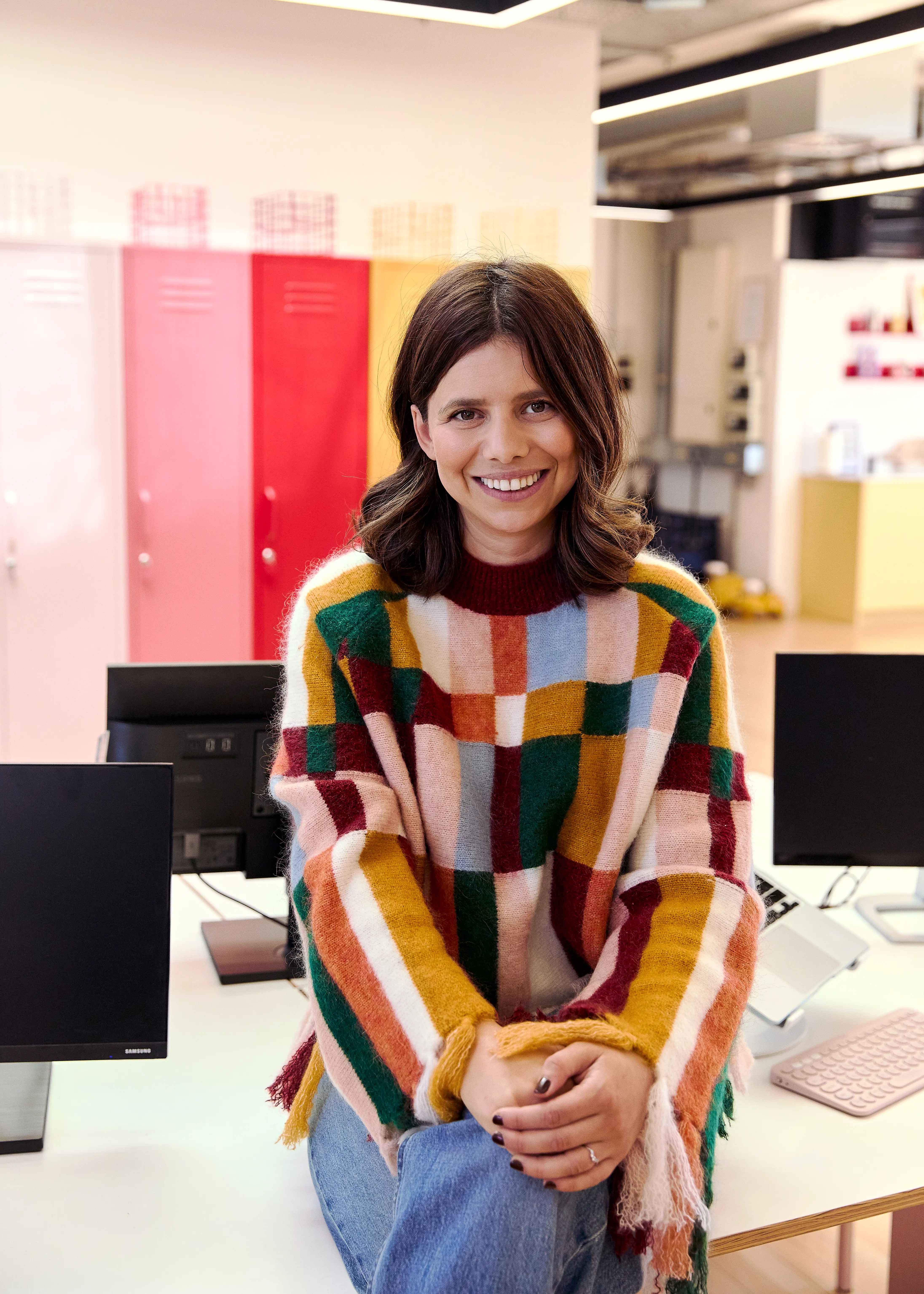 Jess Stern, co-founder of Mustard Made, sitting on a desk in their London office.