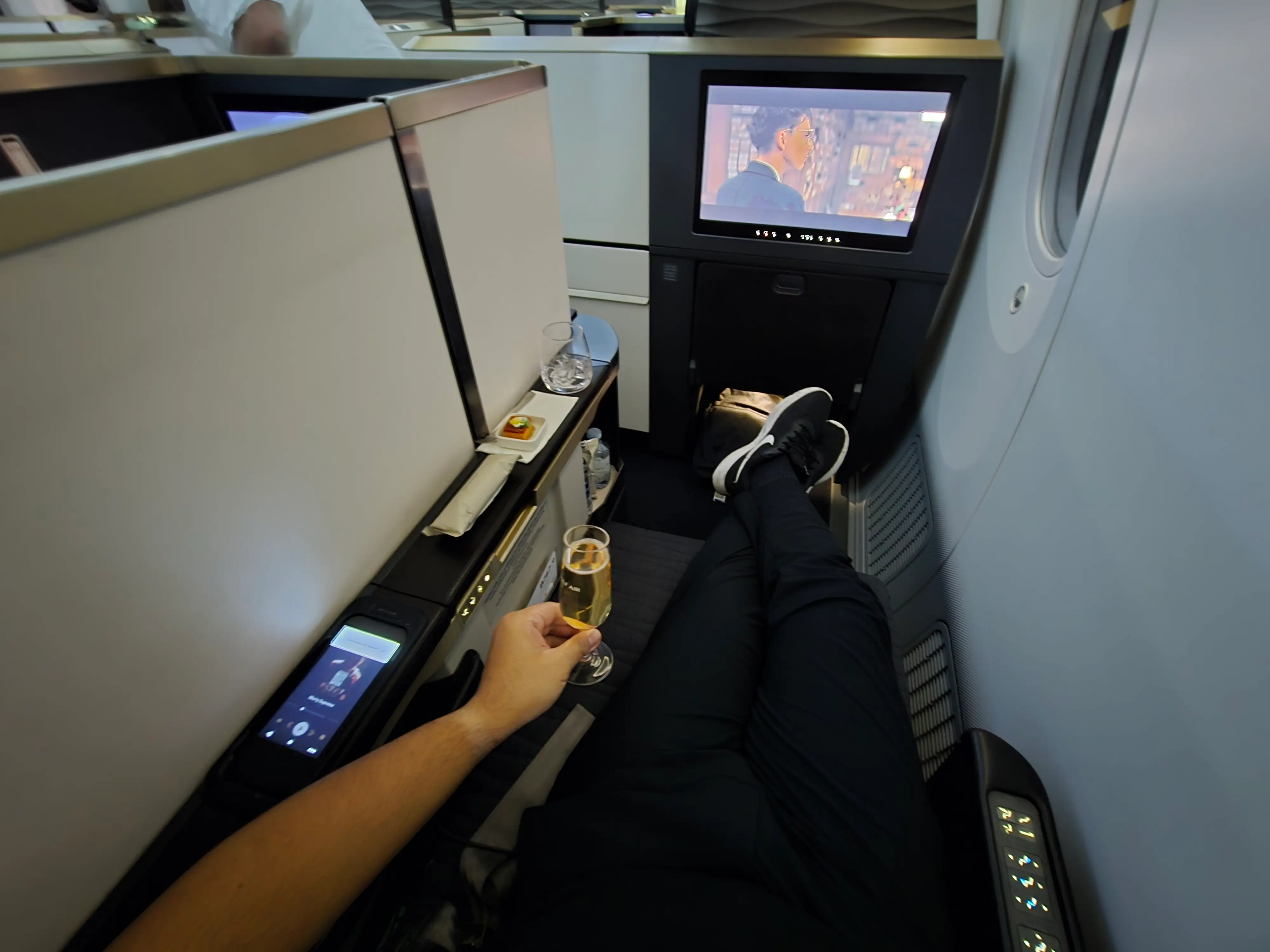A top down view of the author in the seat with the inflight screen ahead.