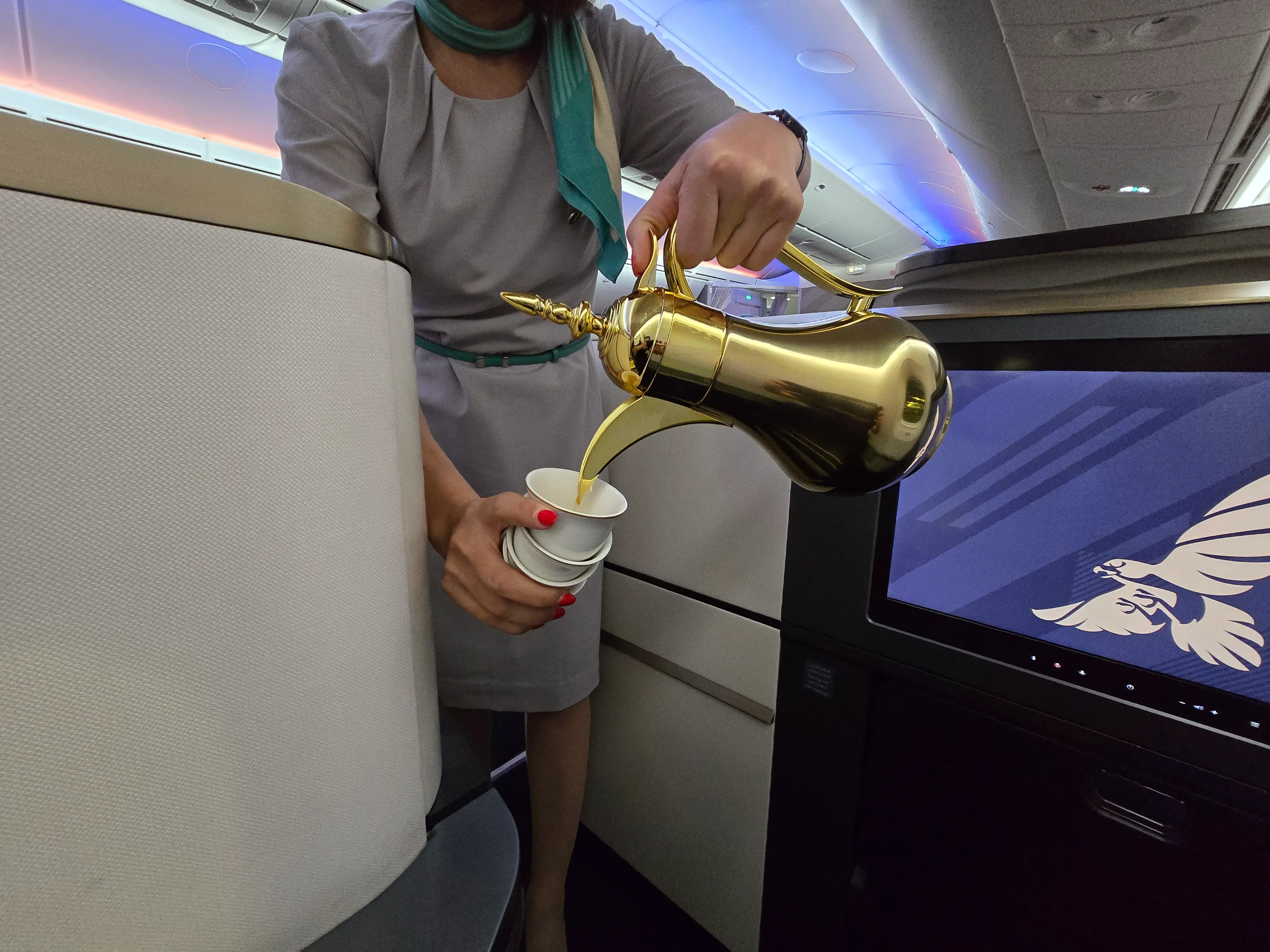A flight attendant pouring tea for the author out of a gold tea pot.
