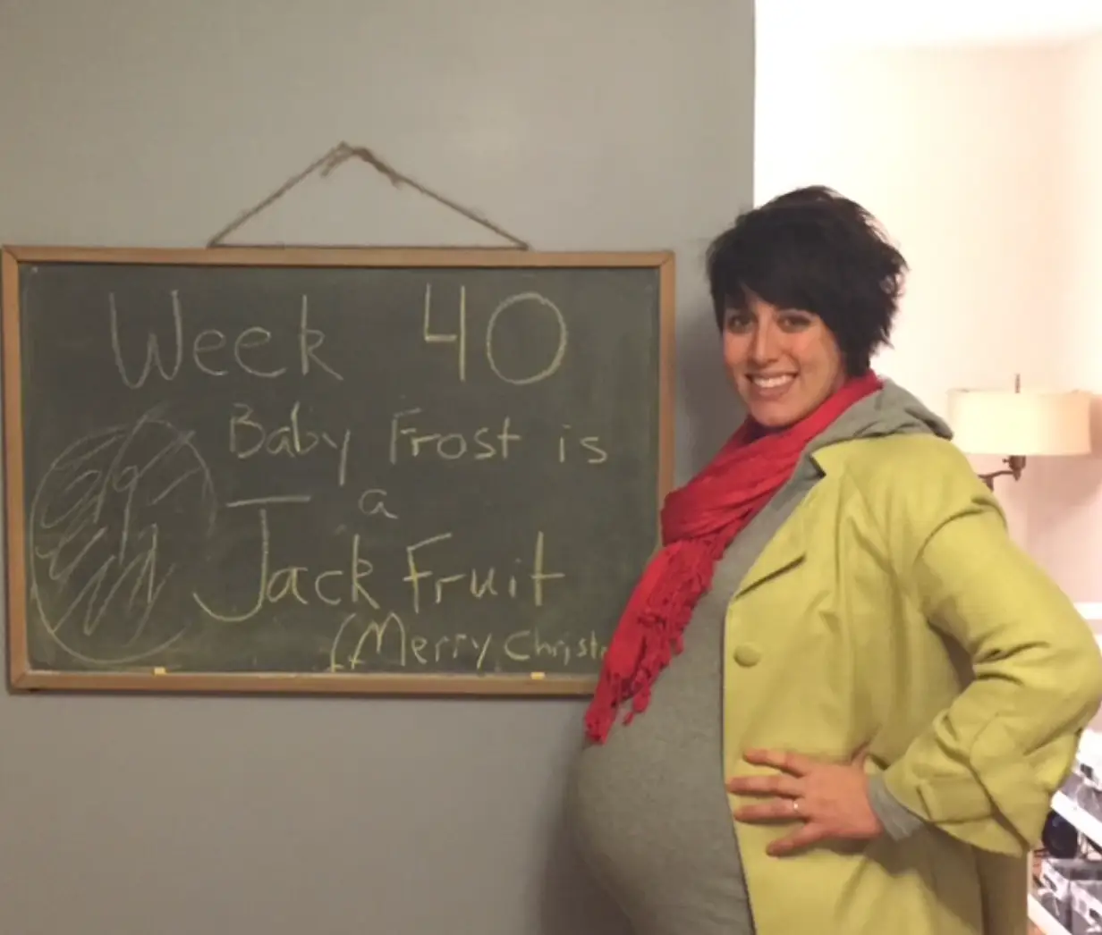 Woman pregnant standing in front of chalkboard sign