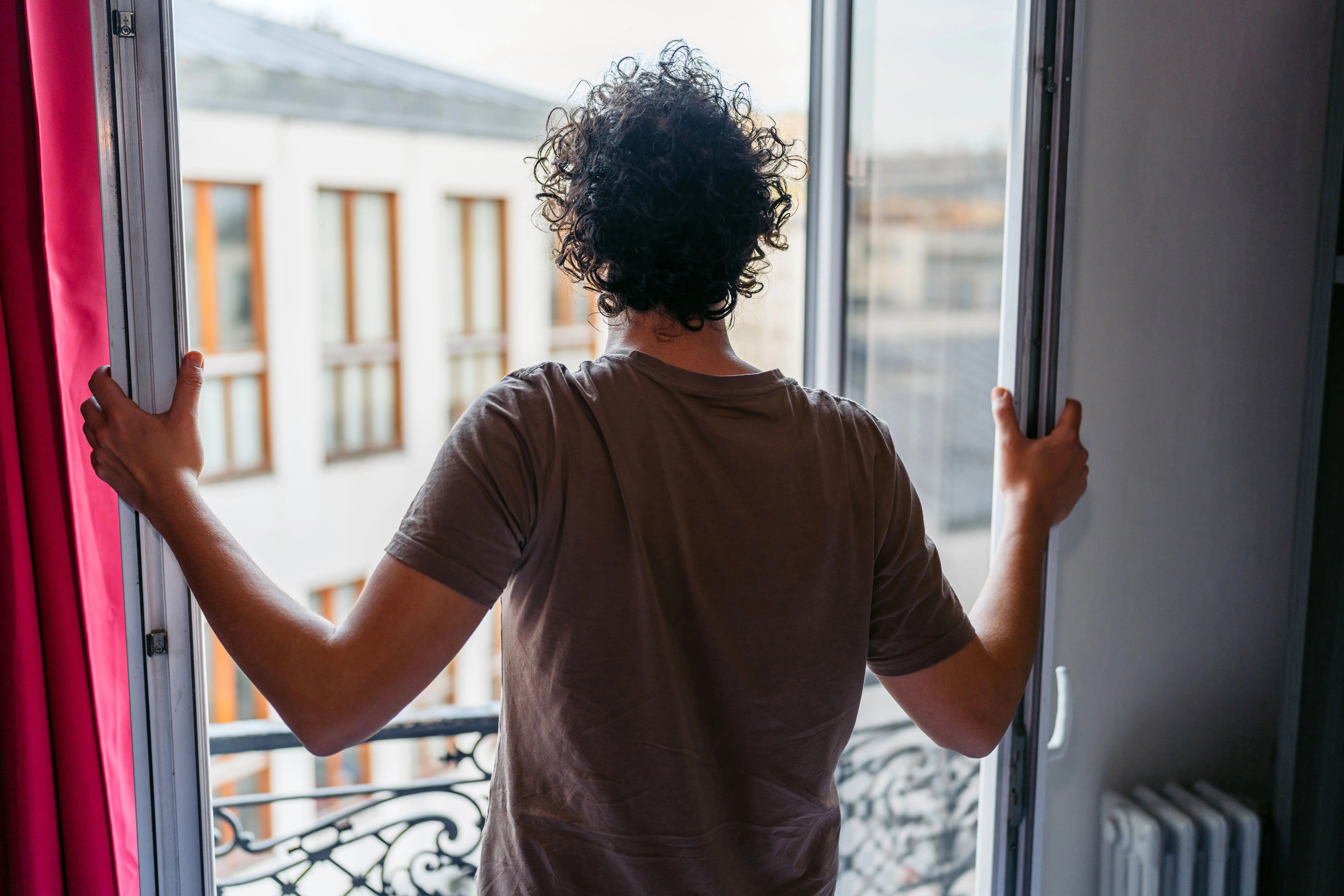Young man opening up the window in the bedroom