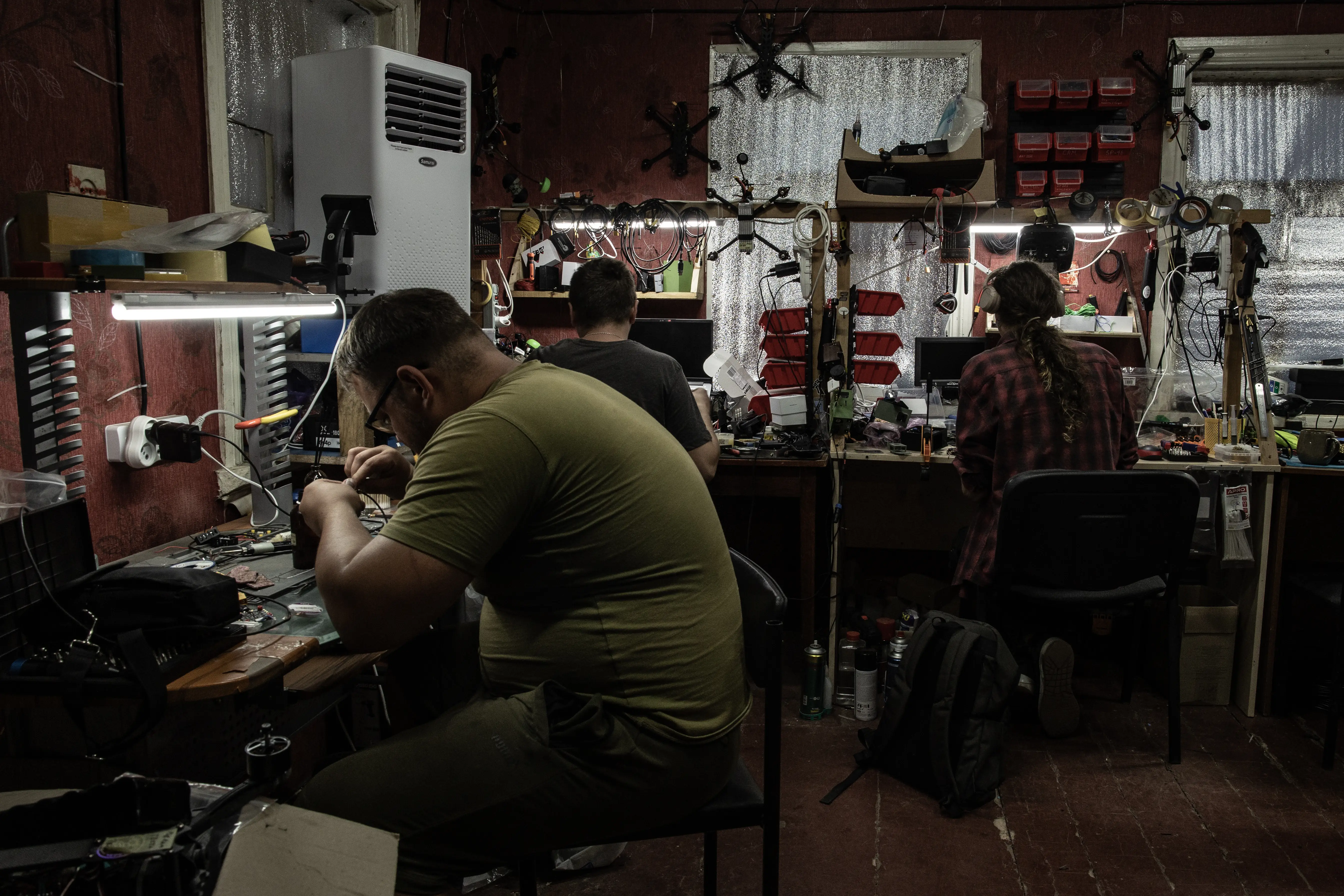 Ukrainian technicians tinker with electronics at their workbenches.